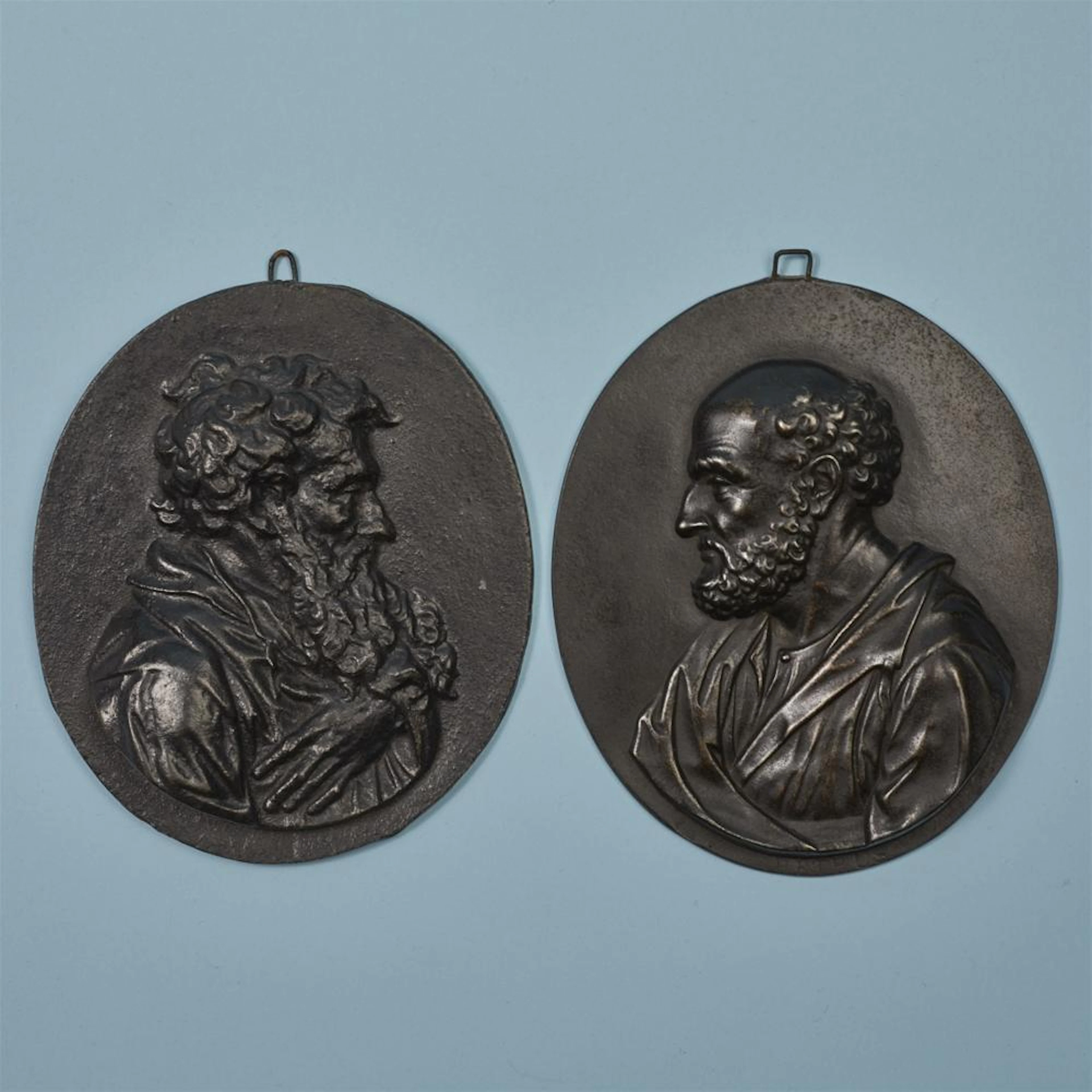 Two oval cast iron plaques