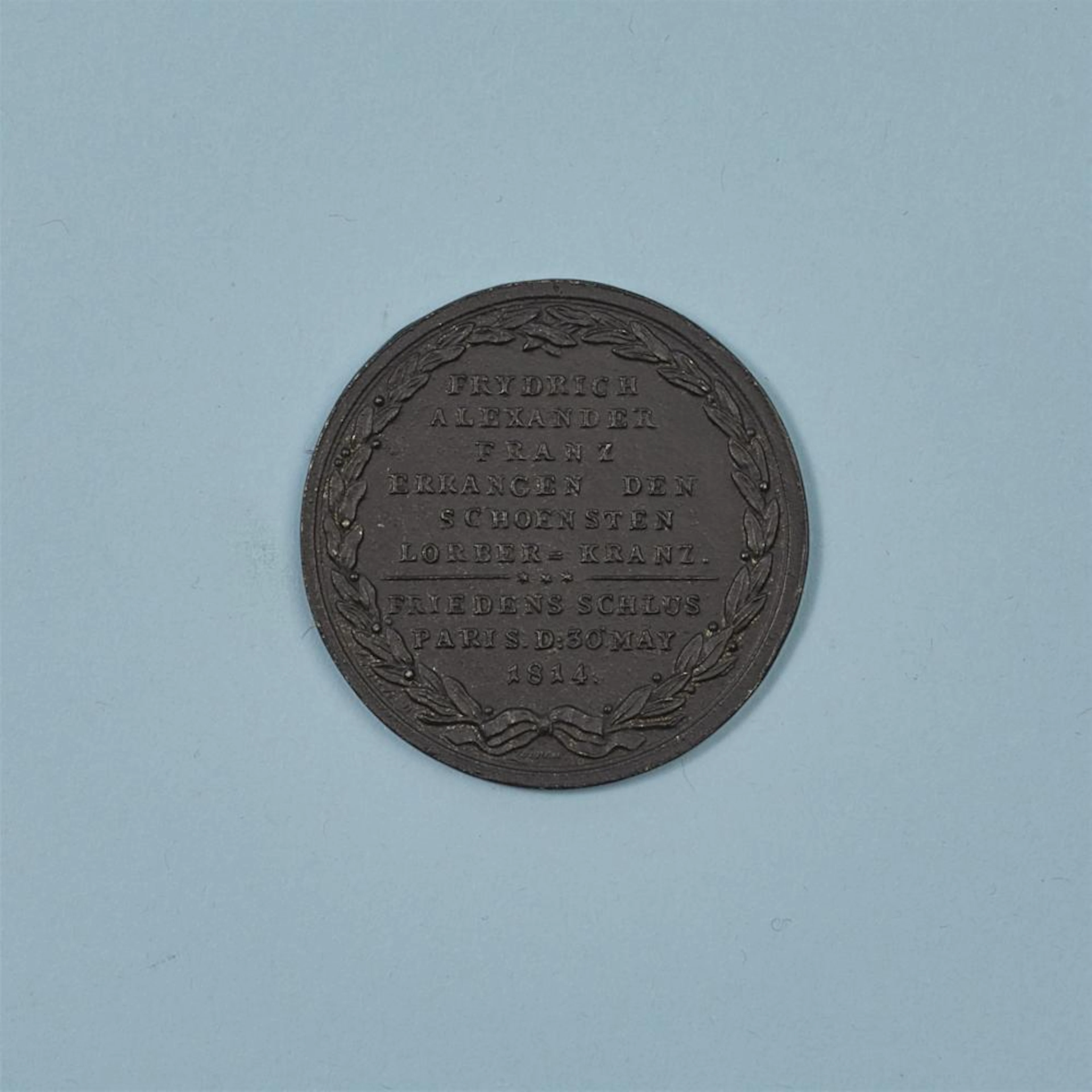 A cast iron medallion "Frydrich, Alexander, Franz errangen den schoensten Lorber-Kranz"