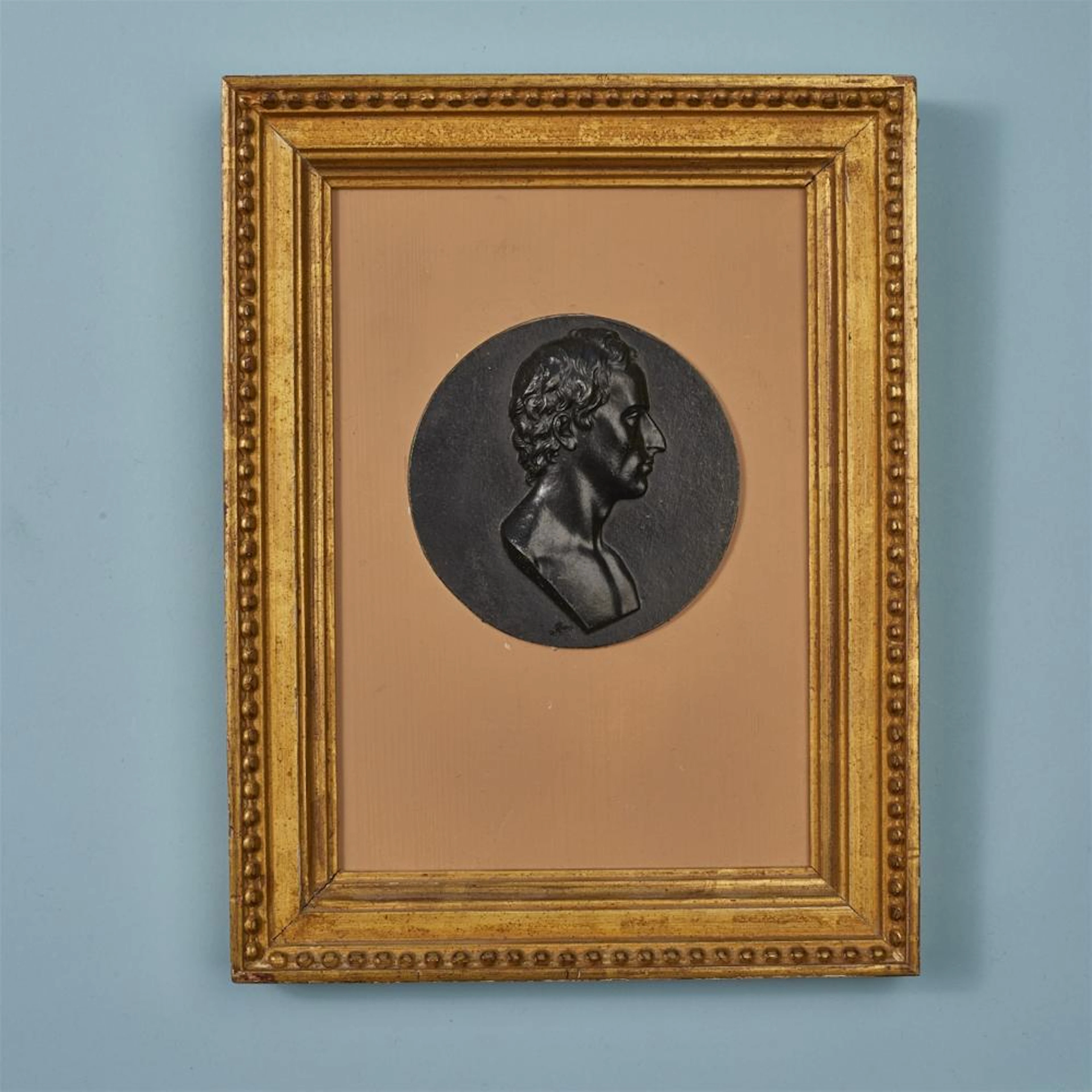 A round cast iron plaque with a portrait of Friedrich von Schiller
