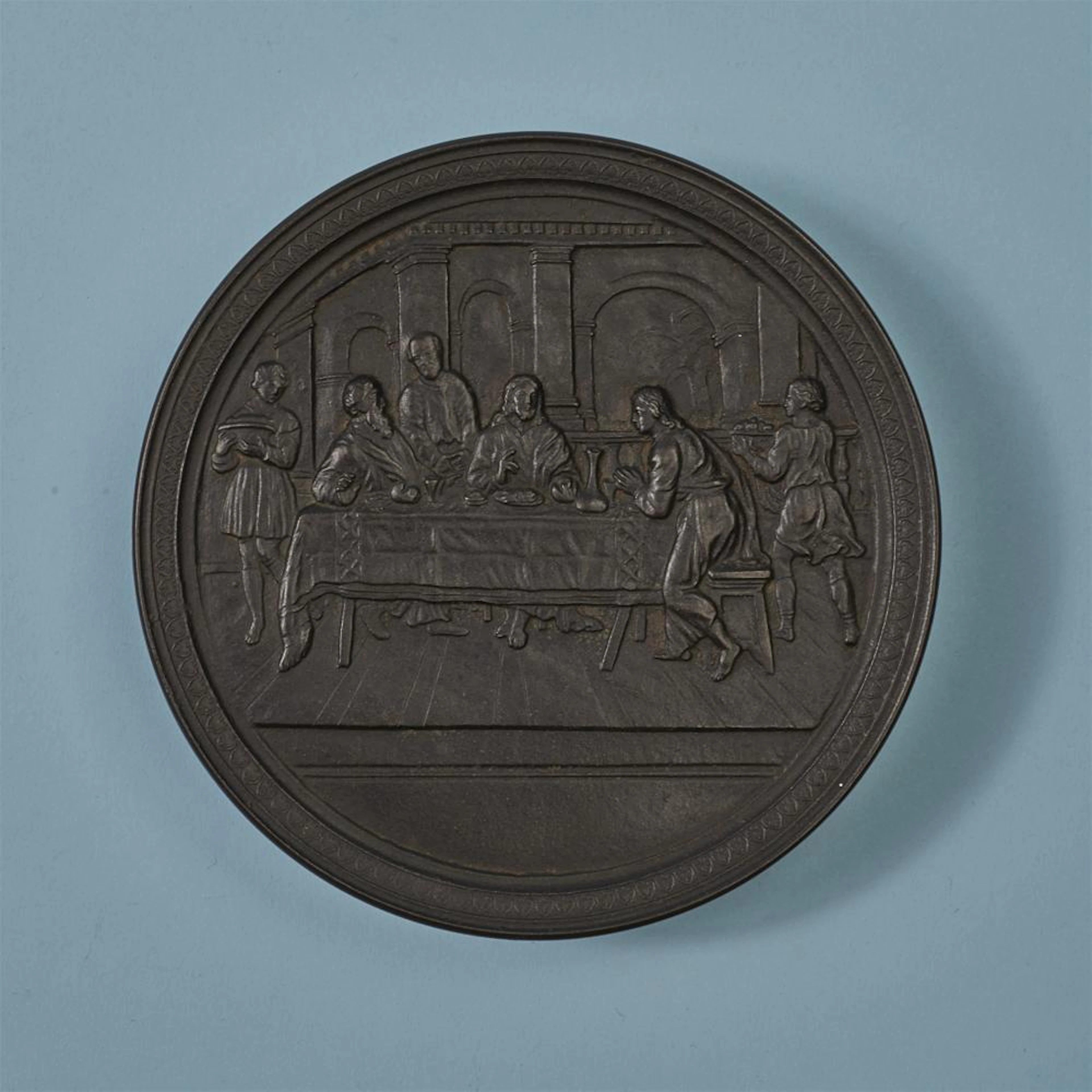 A large round cast iron box with the Supper at Emmaus