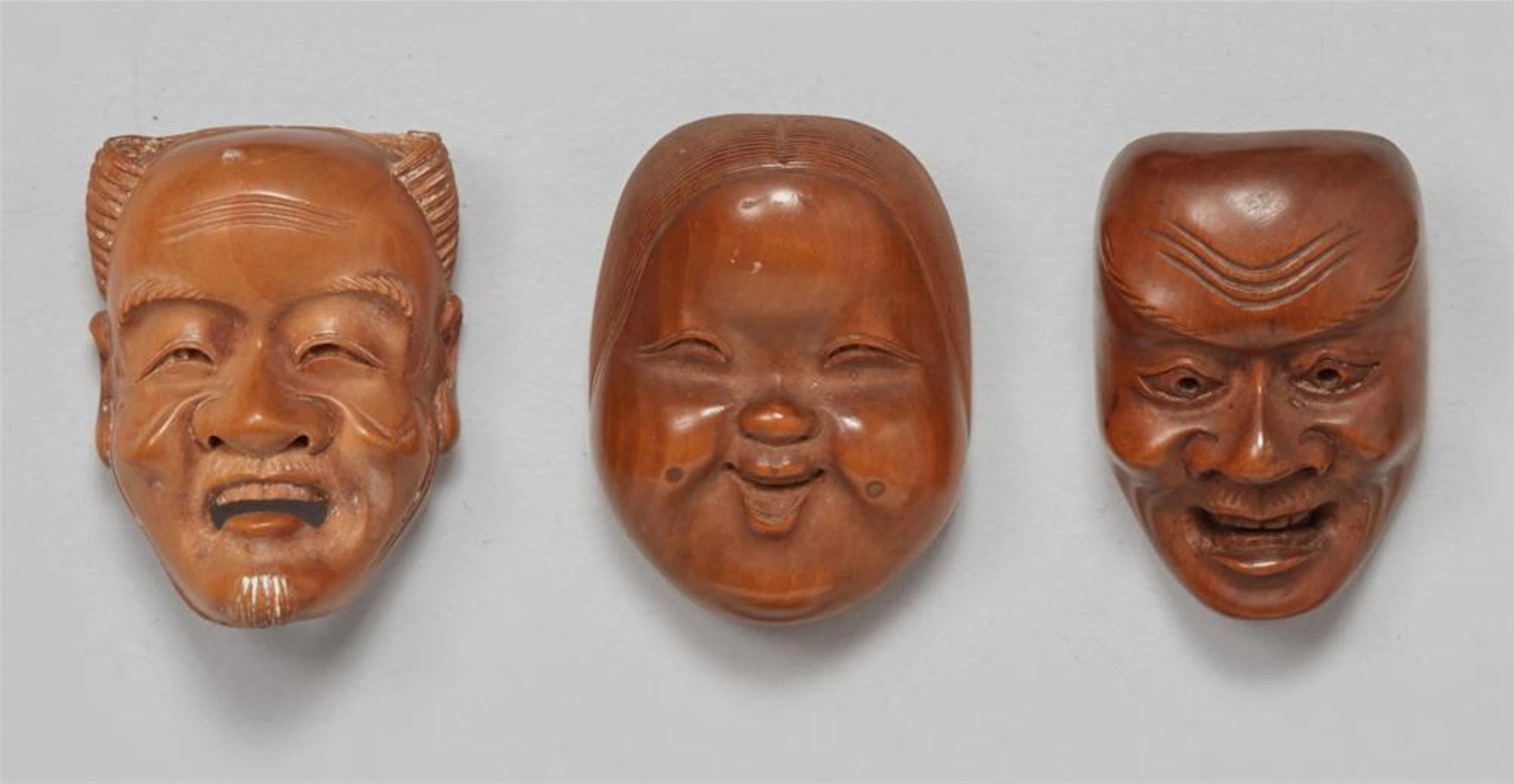 Three boxwood mask netsuke from a set. Around 1900