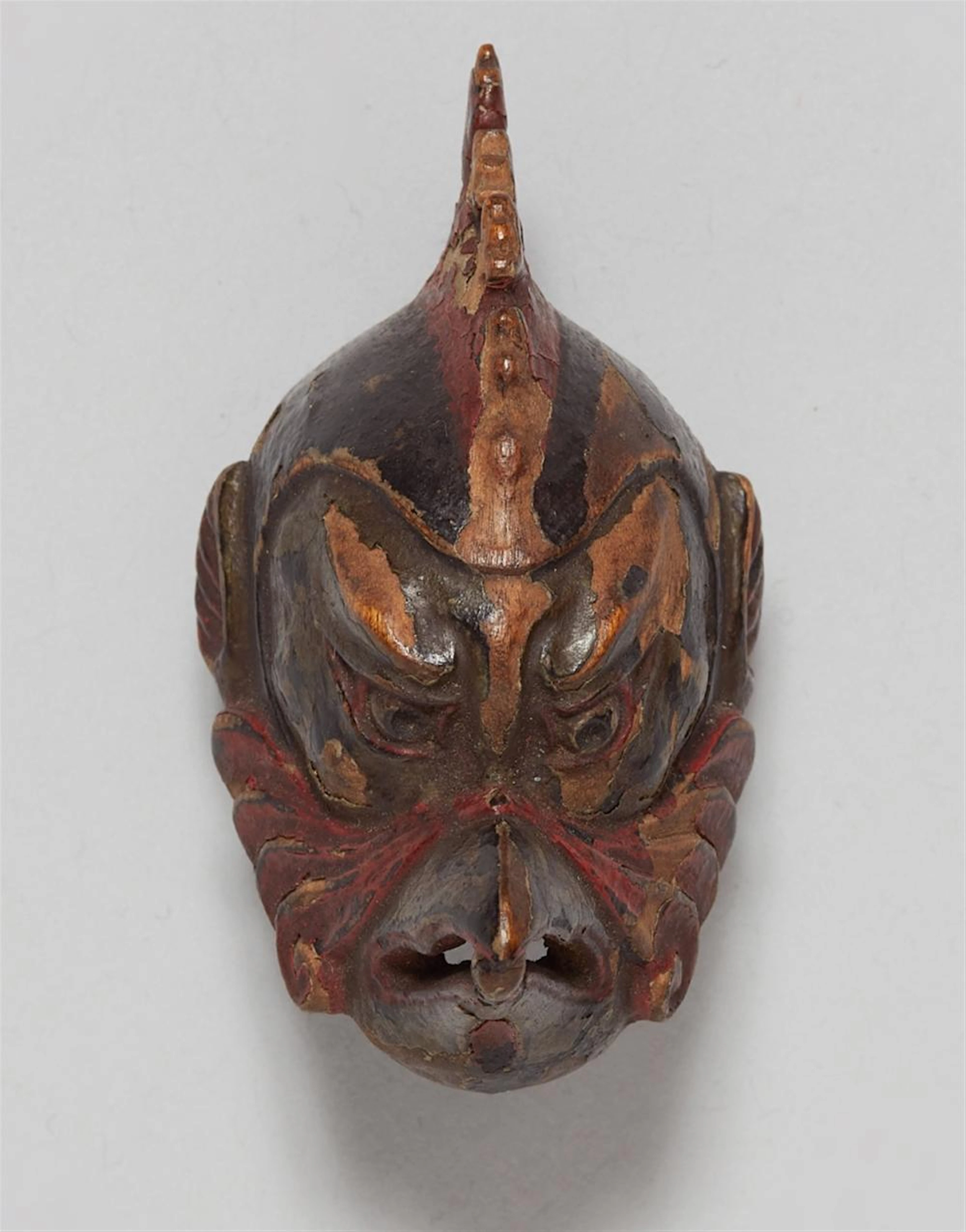 A laquered wood netsuke of a Karura mask. Late 19th century