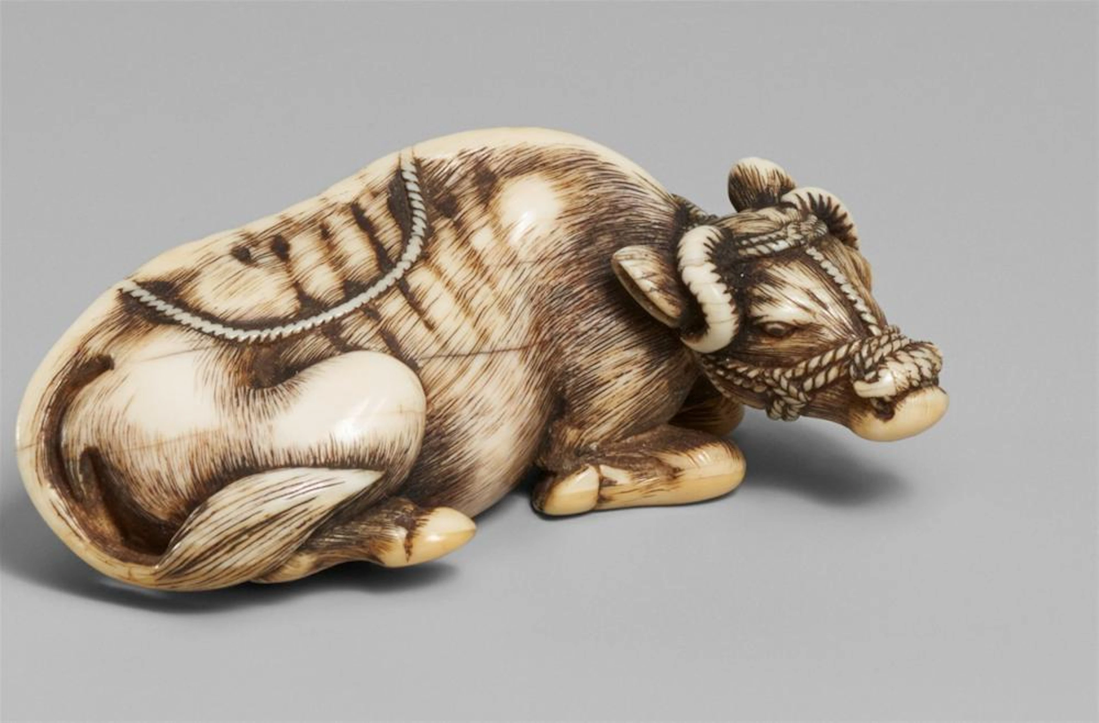 A very fine Kyoto school ivory netsuke of a recumbent ox, by Masanao. Late 18th century
