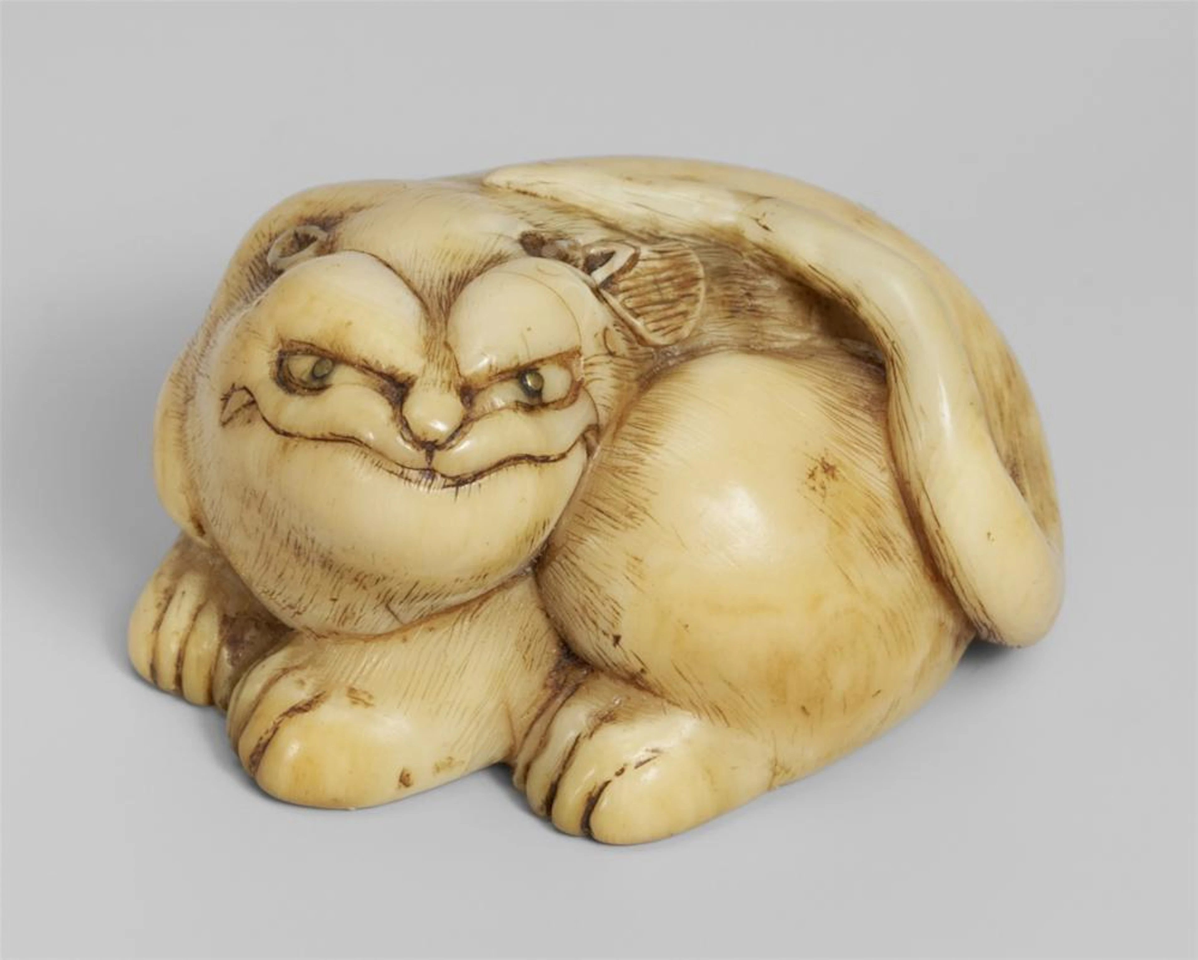 An ivory ash tray netsuke of a recumbent tiger. Early 19th century