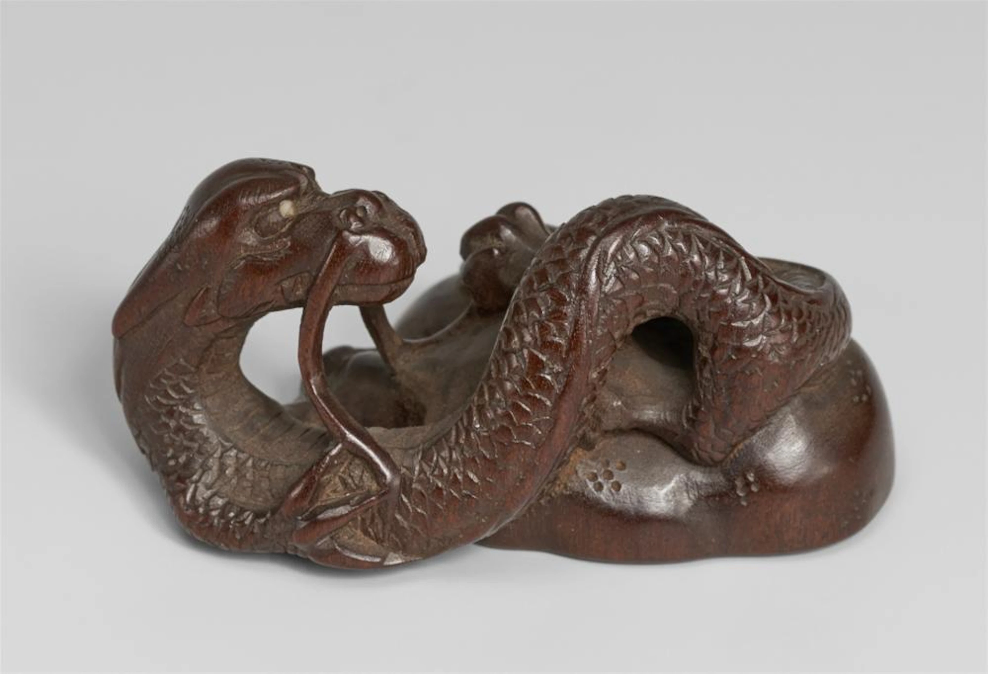A wood netsuke of a slender two-horned dragon. 19th century