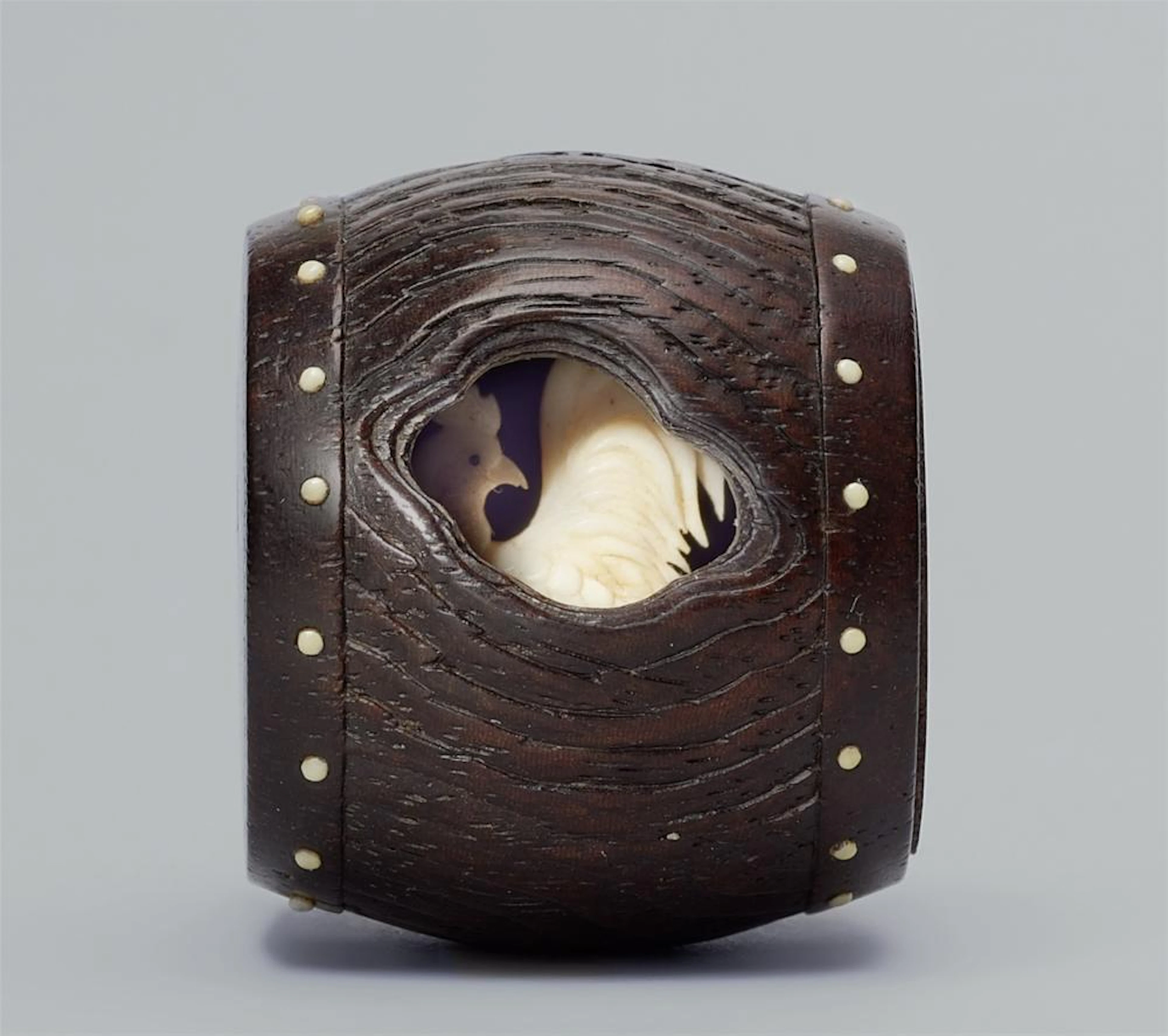 A wood and ivory netsuke of a rooster inside a drum. Mid-19th century