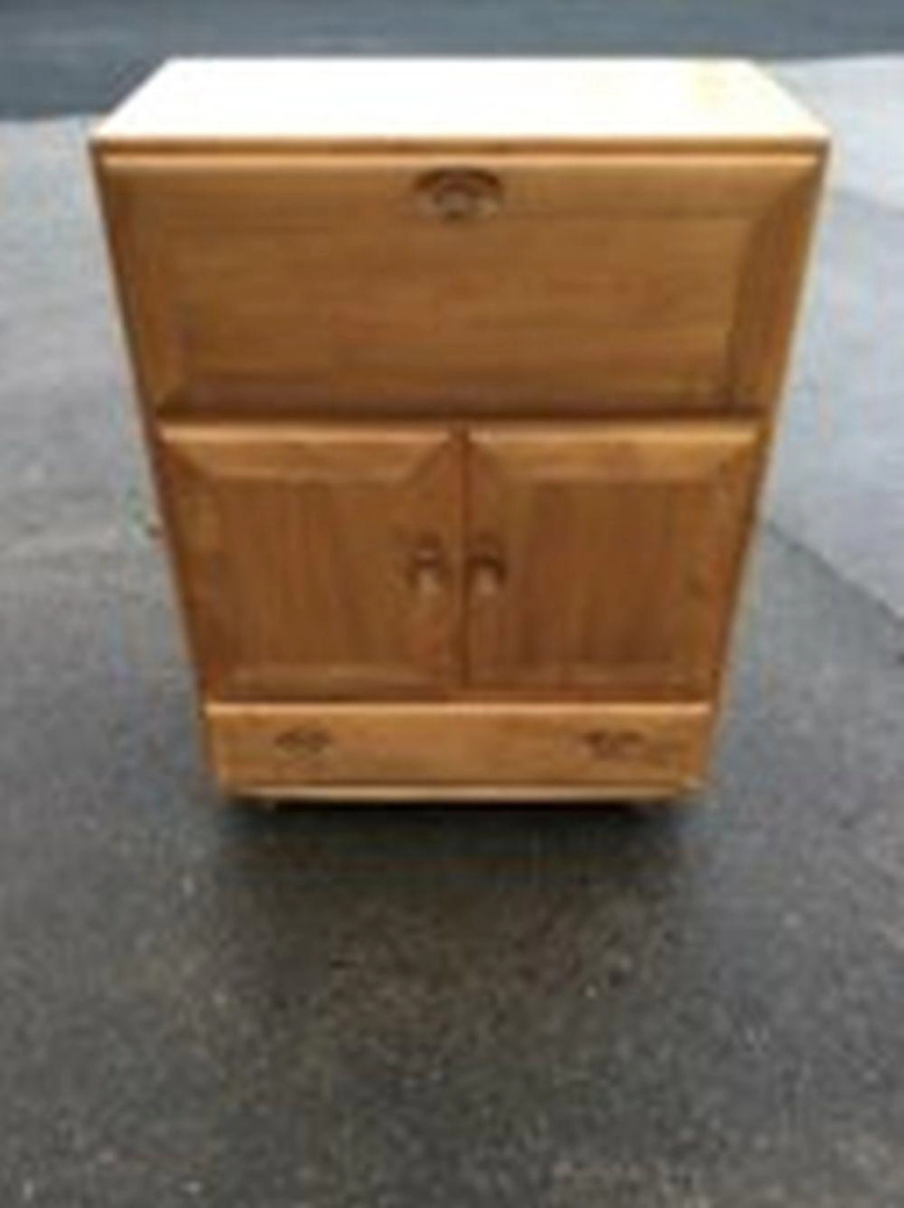 A 70s Ercol elm secretaire with panelled drop-down compartment above two-d
