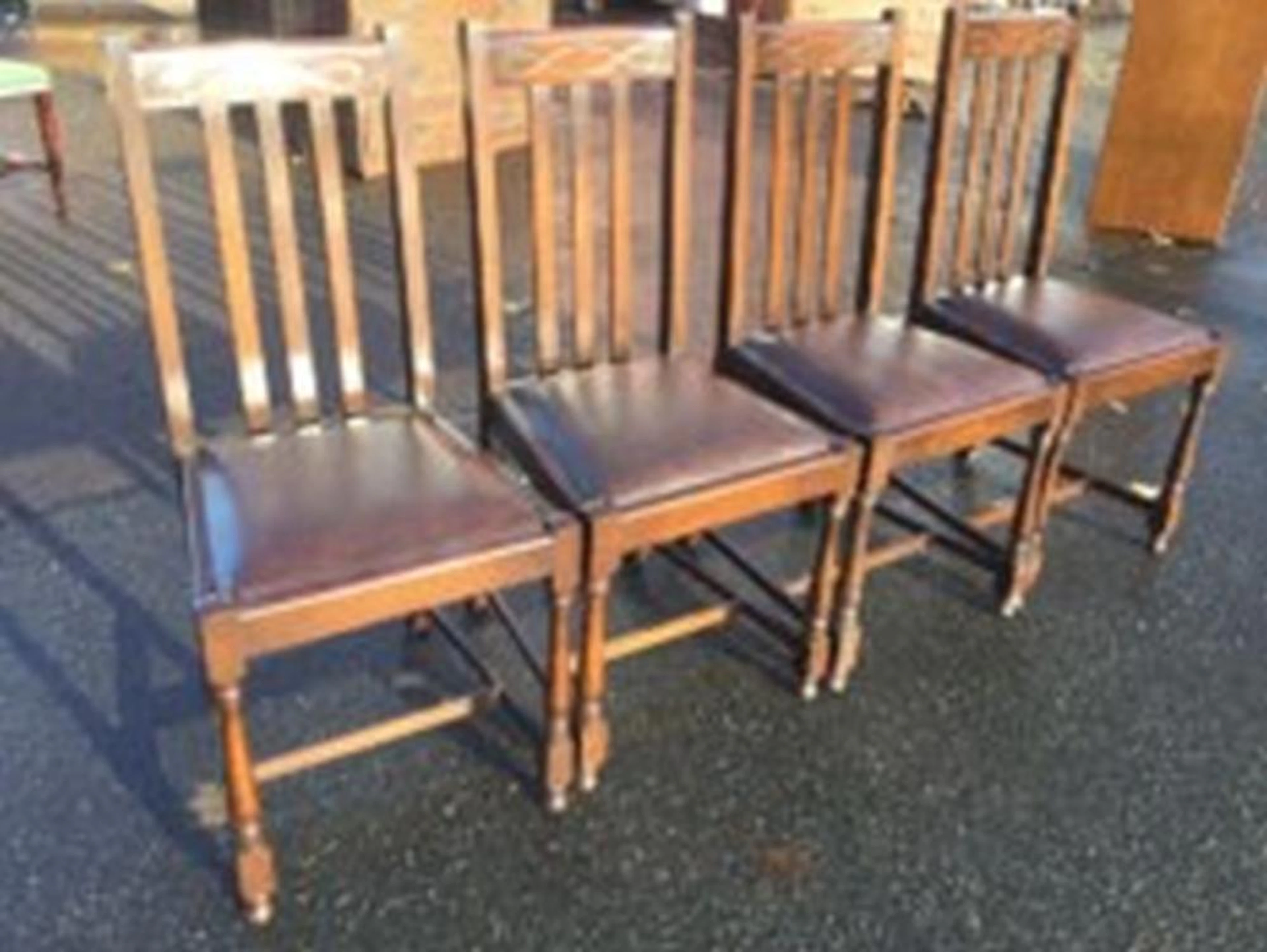 A set of four oak dining chairs, the back rails carved with loop bands abo