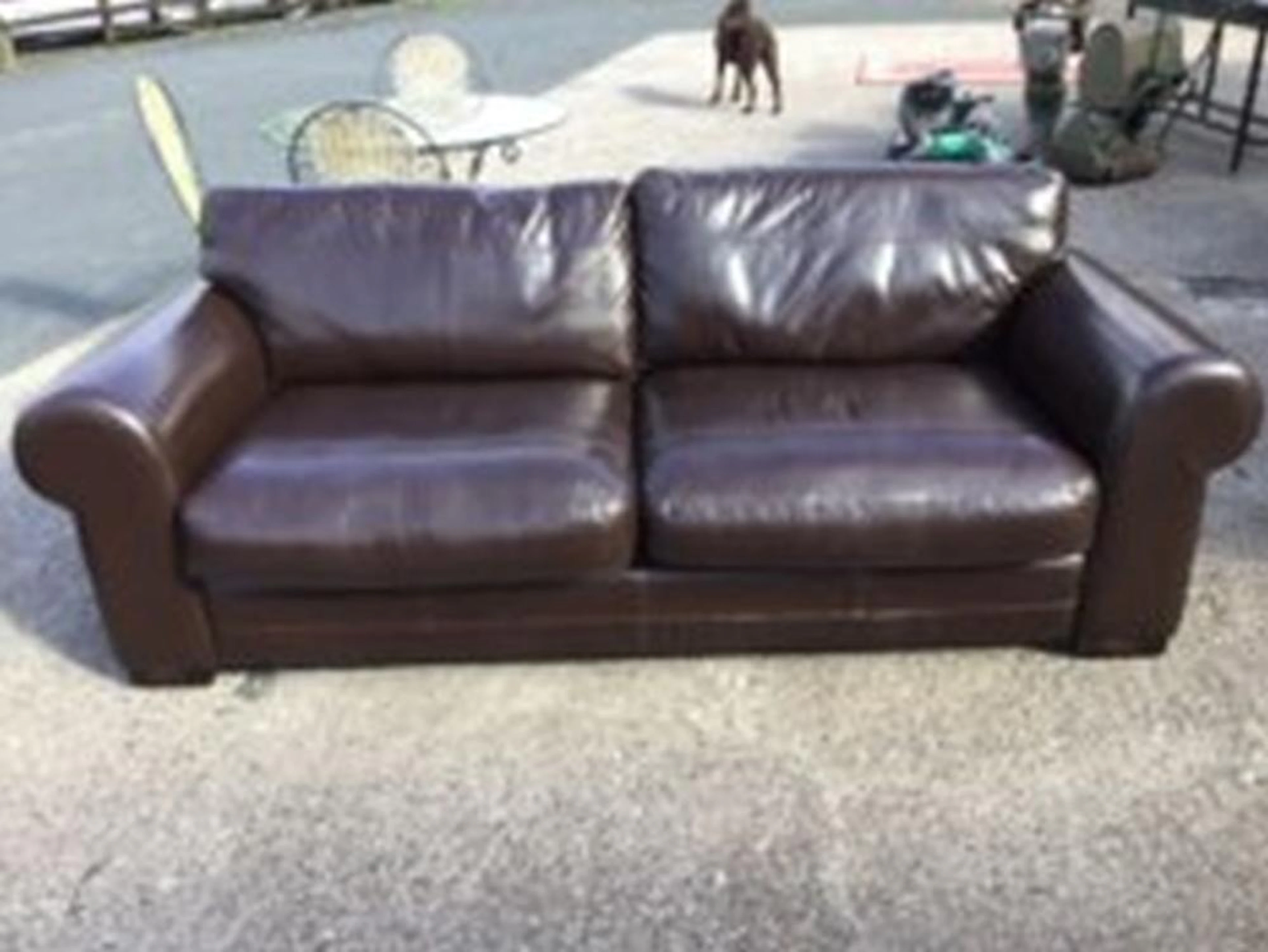A large leather upholstered three-seater sofa, with loose cushions and pan