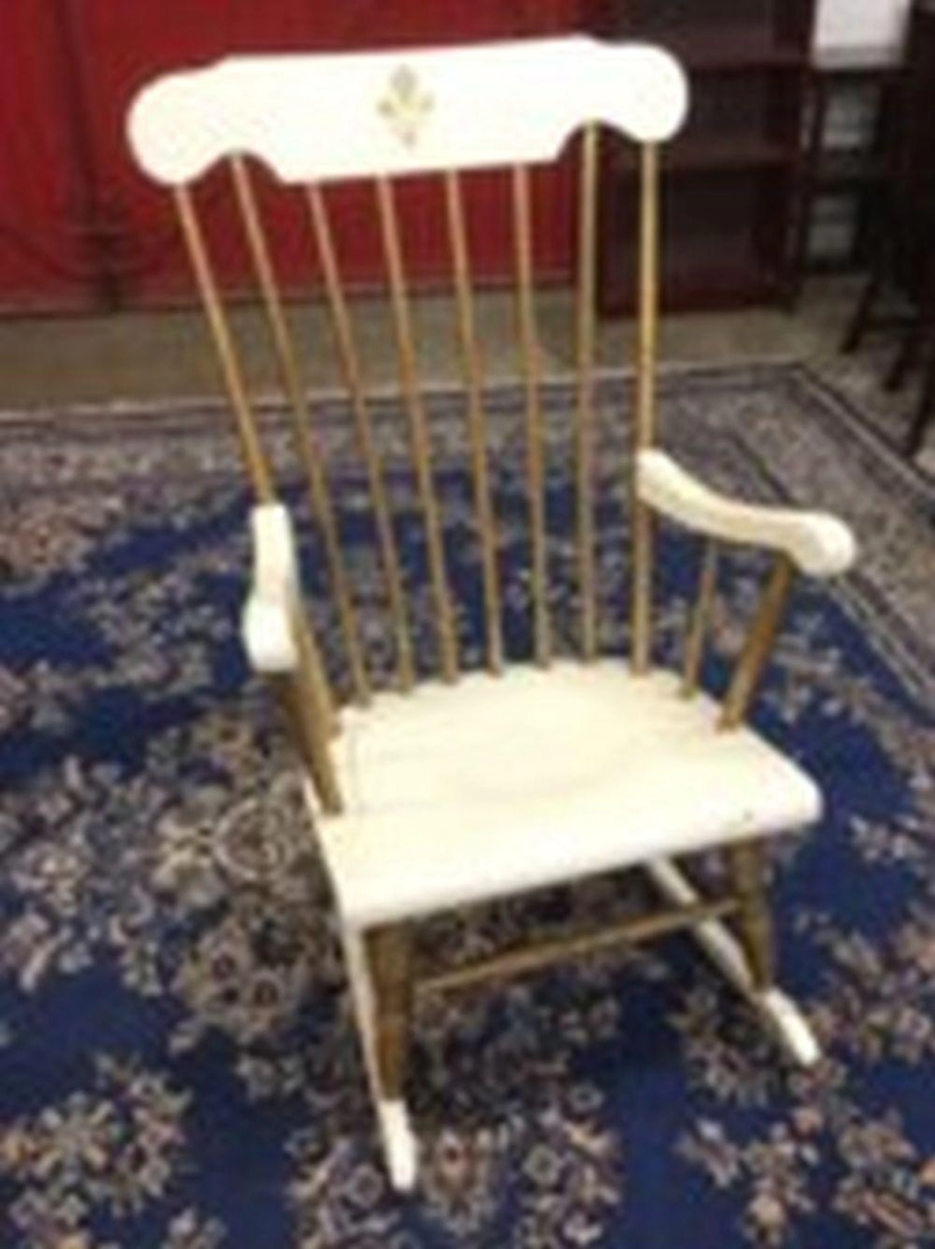 A painted rocking chair with spindle back and shaped arms above a solid se
