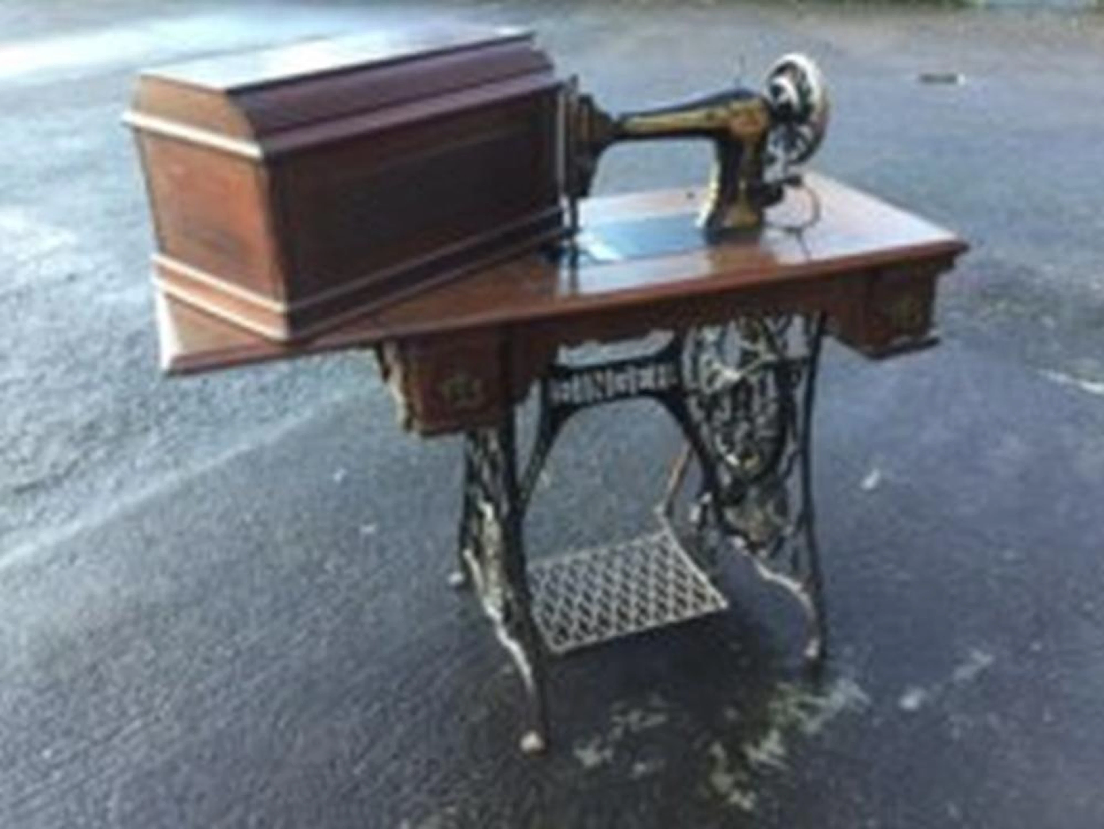 A Singer sewing machine on walnut table with drop-leaf, having three frieze