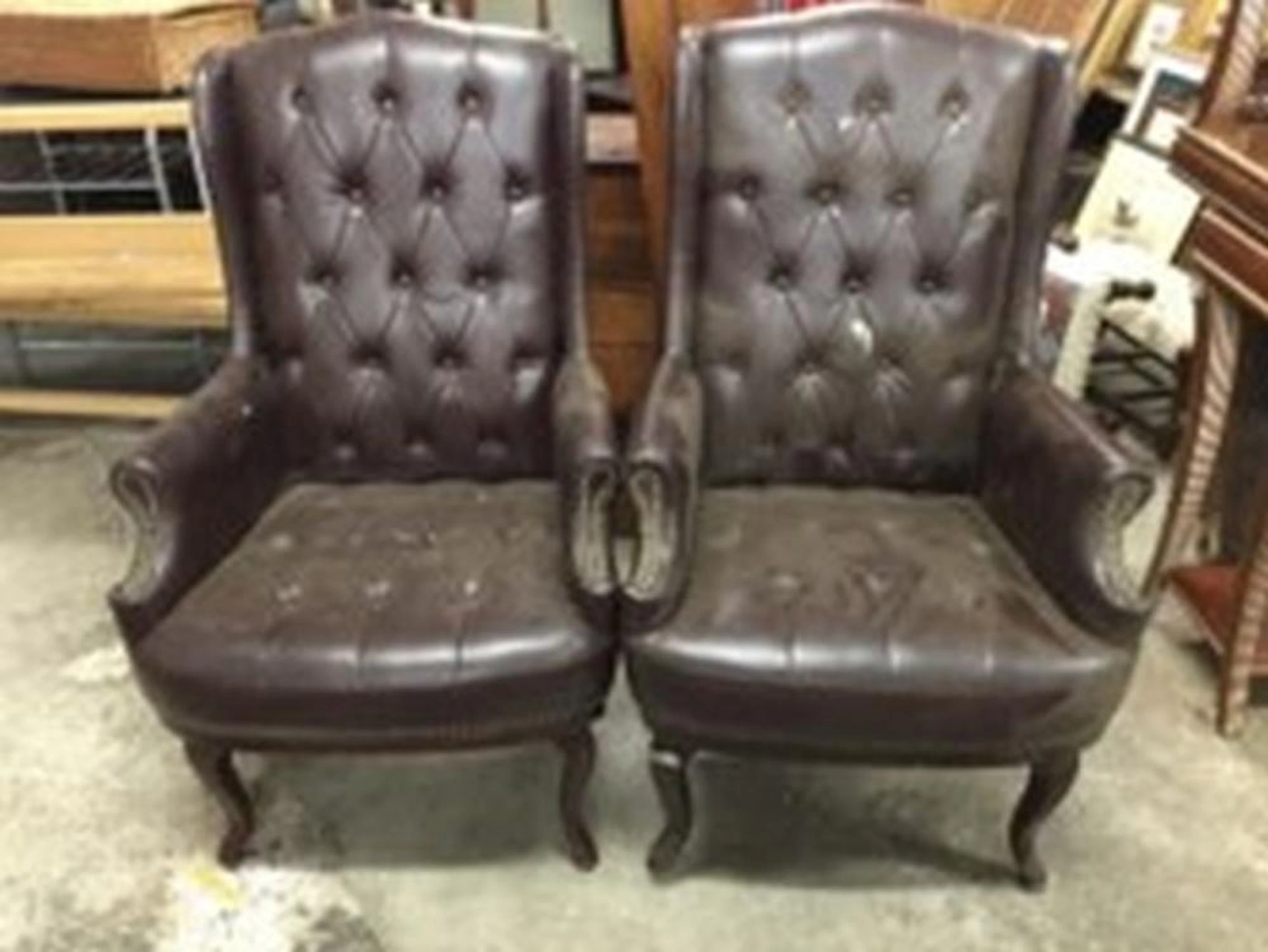 A pair of button upholstered wing armchairs, the high backs above bowfront