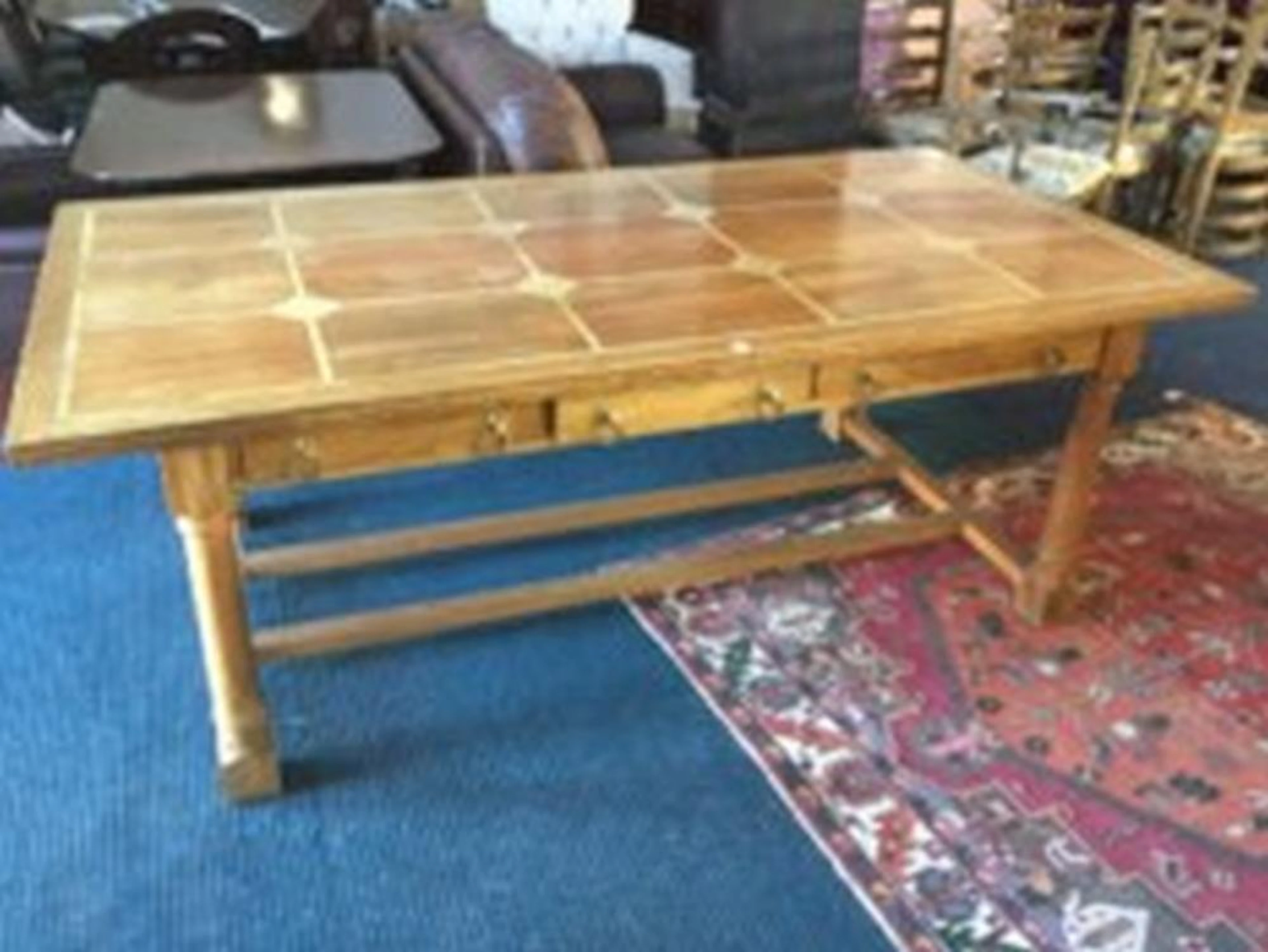 A rectangular hardwood dining table, the parquetry top with panels framed