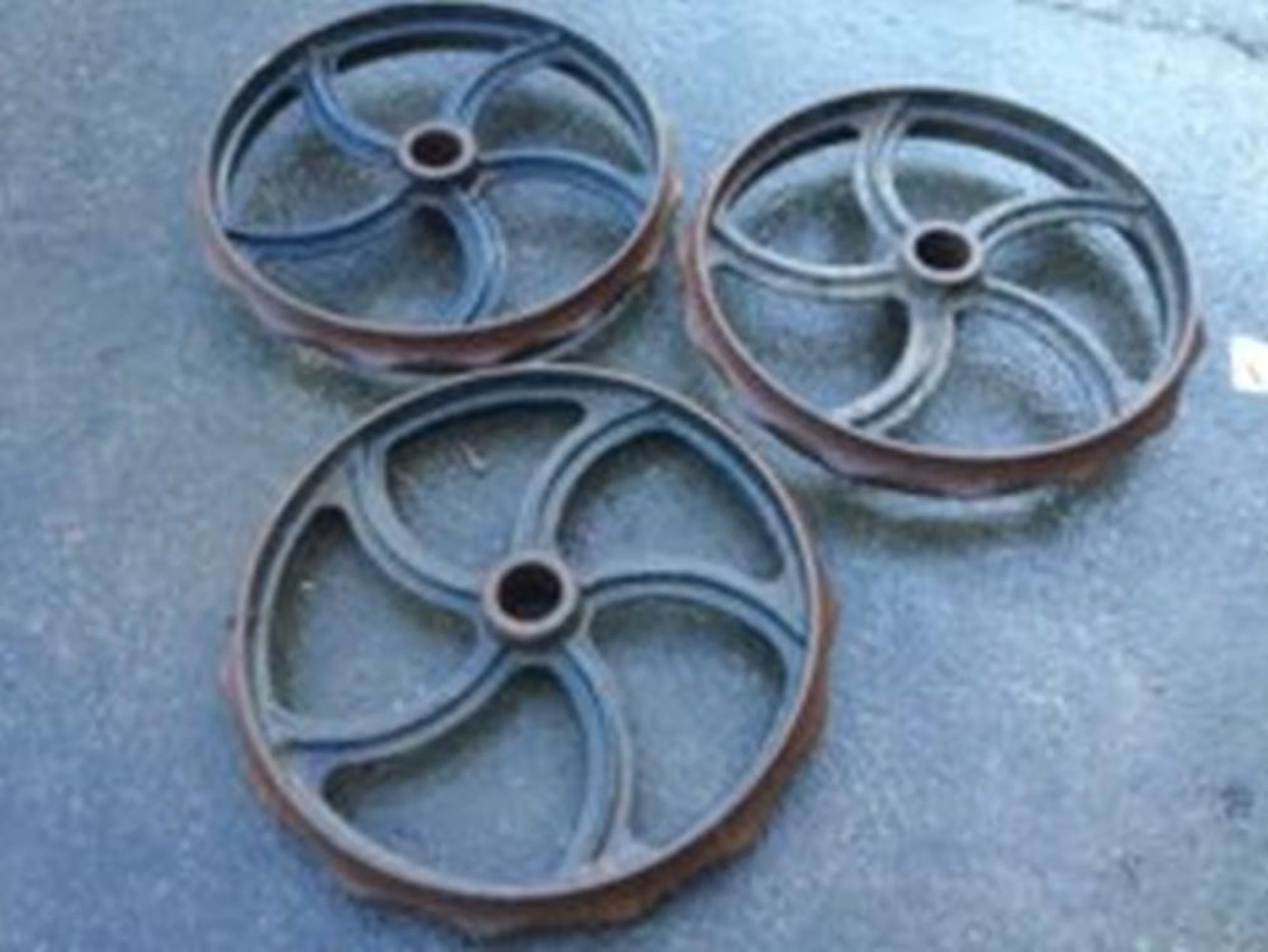 Three cast iron wheels with rippled rims, each having five scroll cast spo