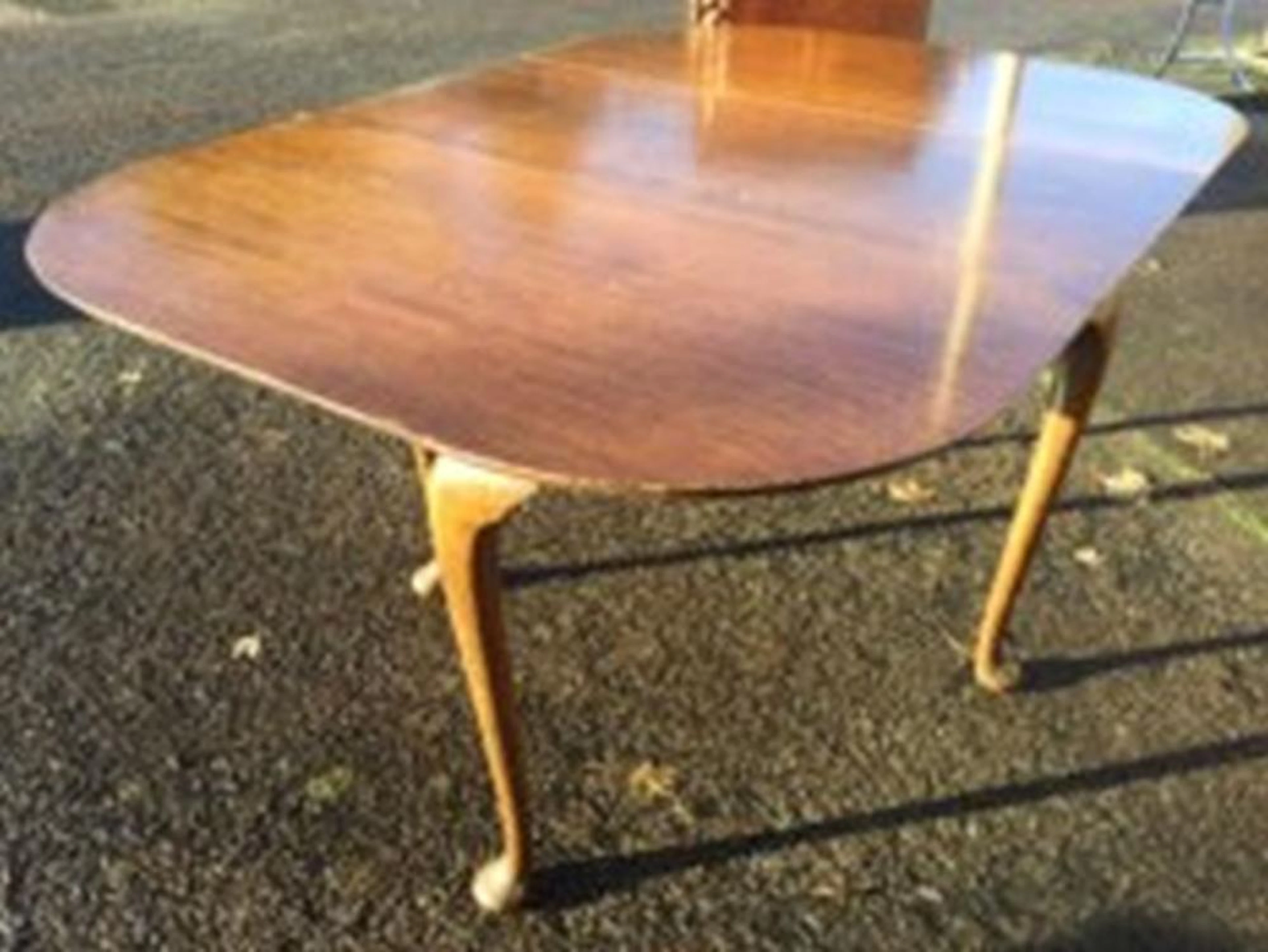A rectangular rounded dining table, the top with drop-leaves raised on cabr