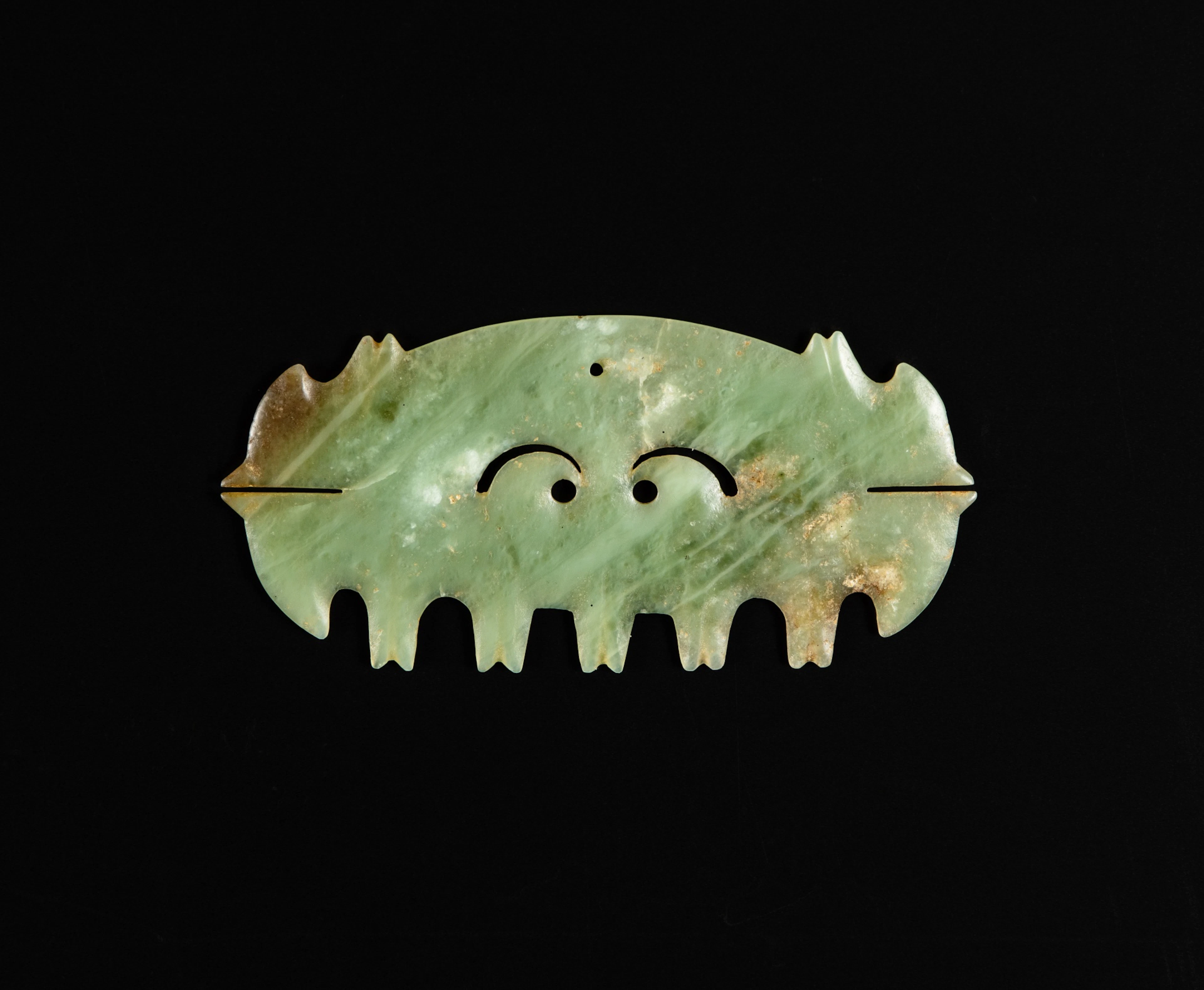 An open work celadon jade 'toothed animal mask' ornament