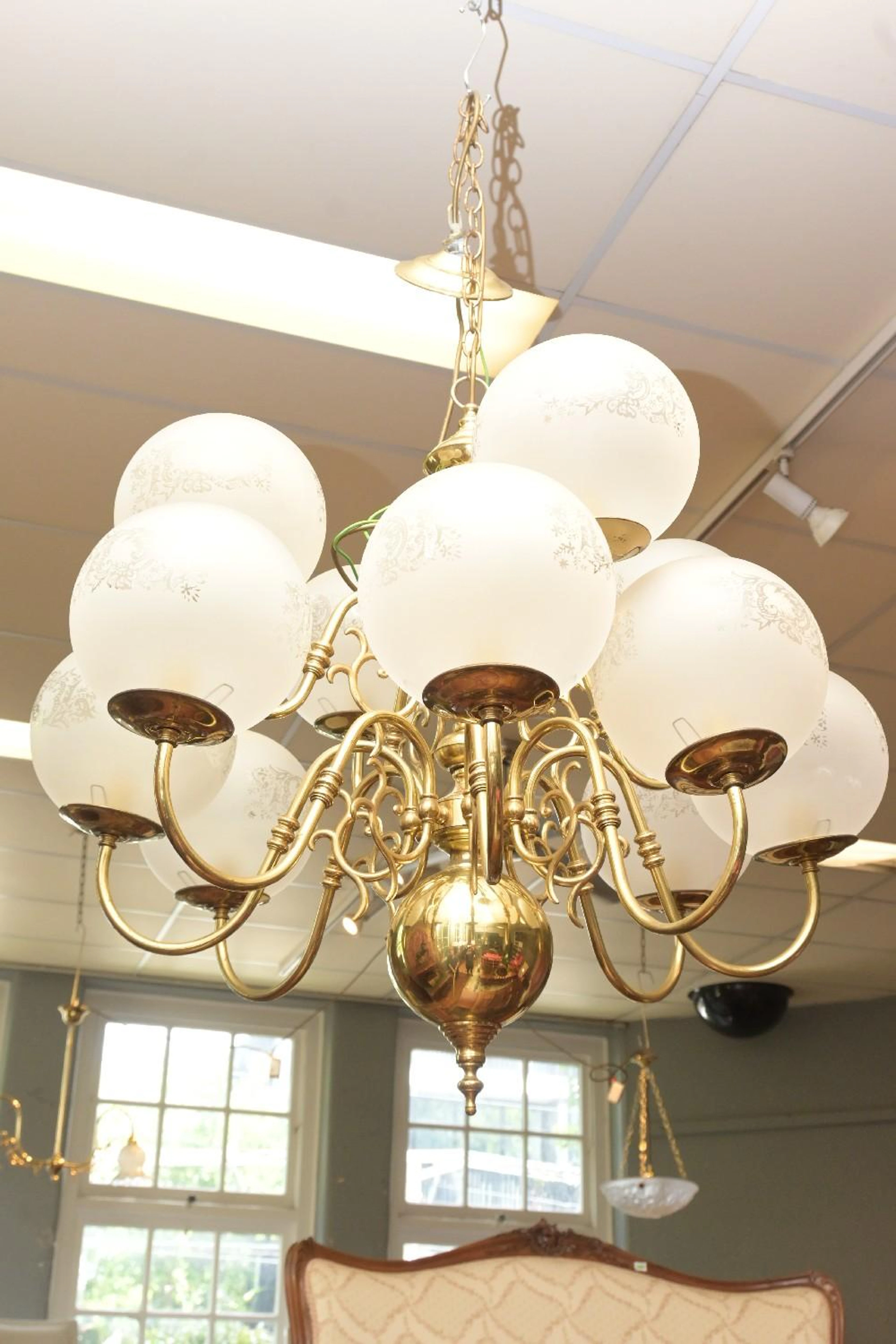A BRASS TWELVE GLOBE CHANDELIER WITH ETCHED GLASS SHADES...