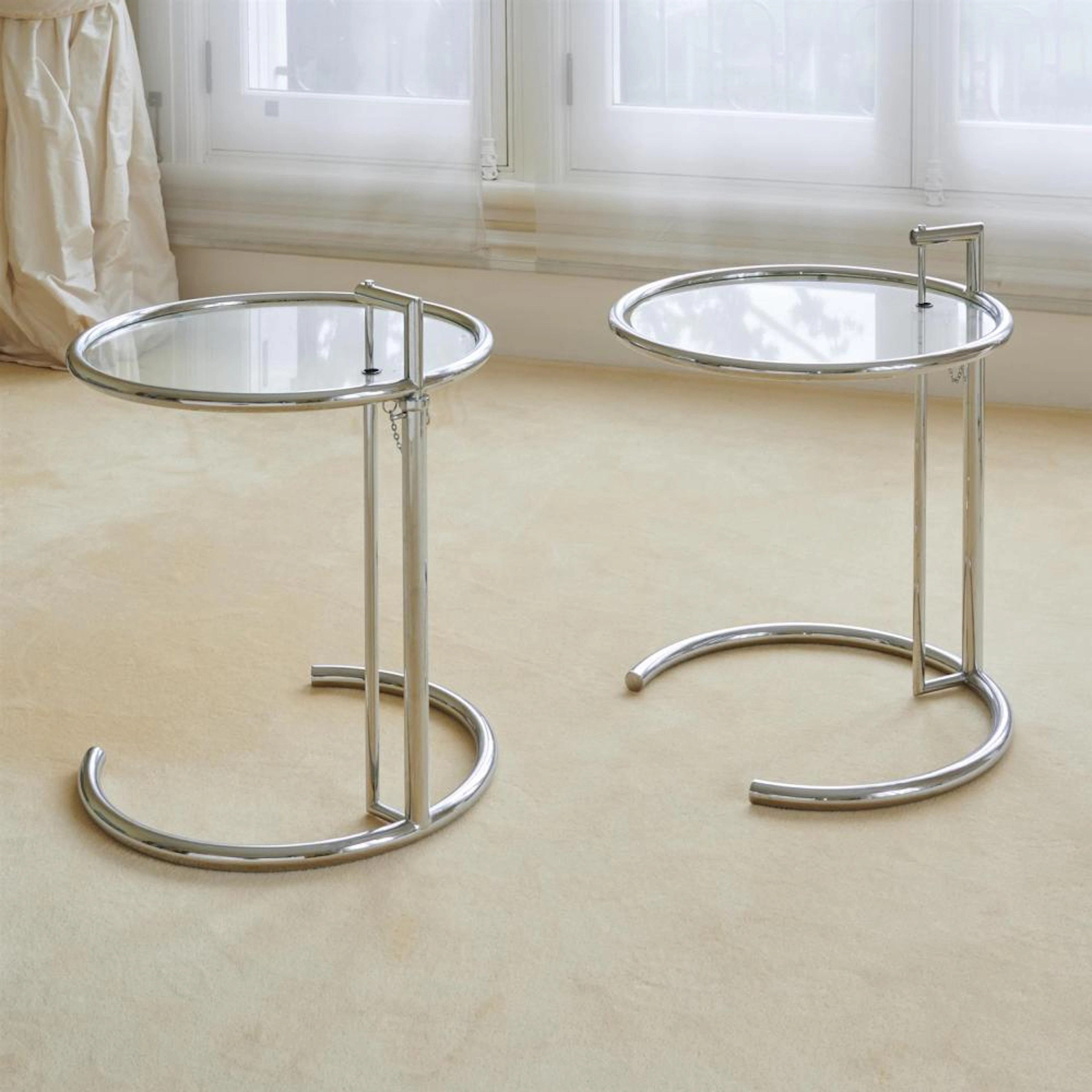 A PAIR OF CHROMED METAL AND GLASS ADJUSTABLE SIDE TABLES...