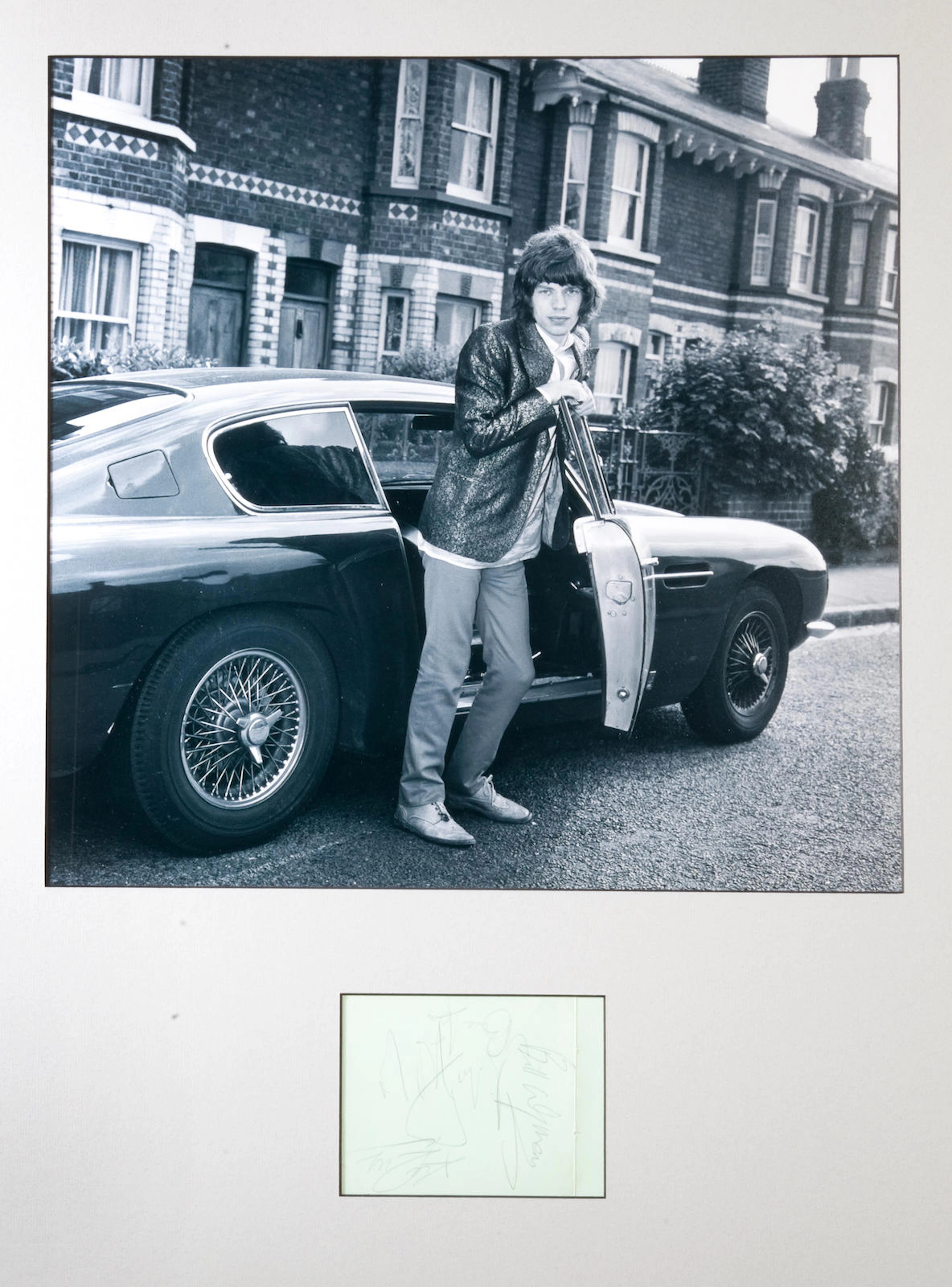 A large photograph of Mick Jagger with his Aston Martin DB6,