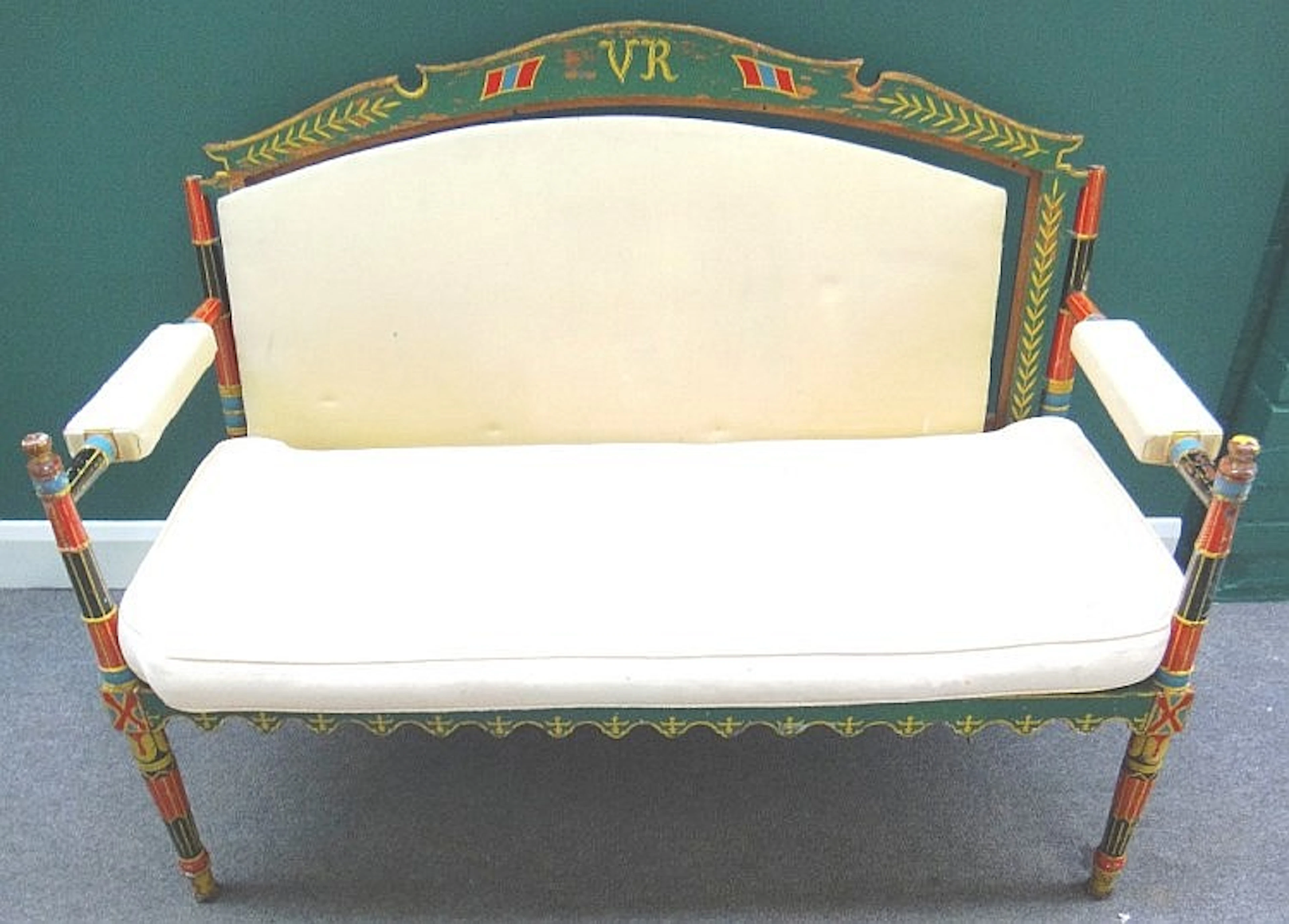 An early 20th century Indian polychrome painted open arm sofa on tapering t
