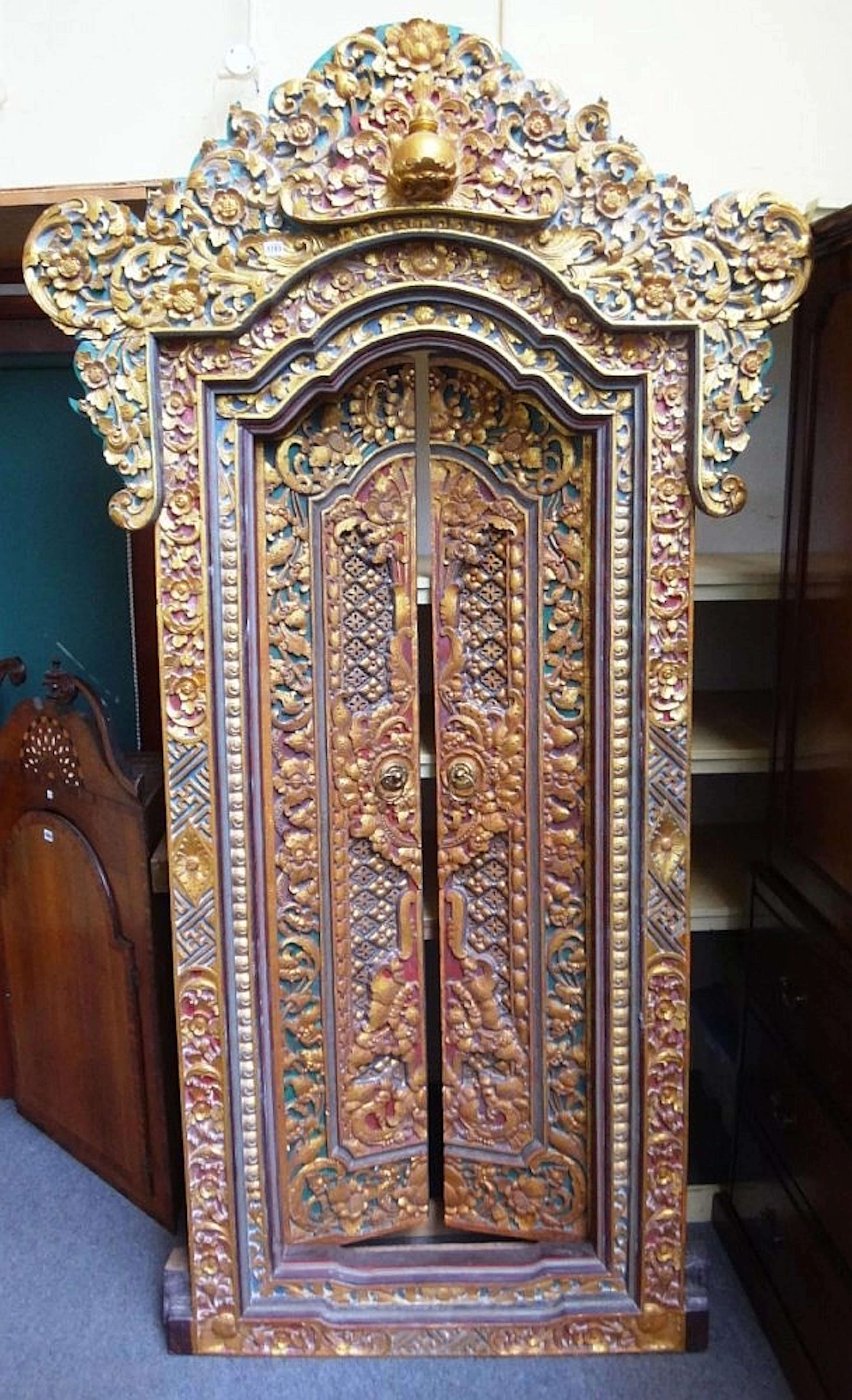 A 20th century profusely carved, painted and gilded Tibetan door and frame,