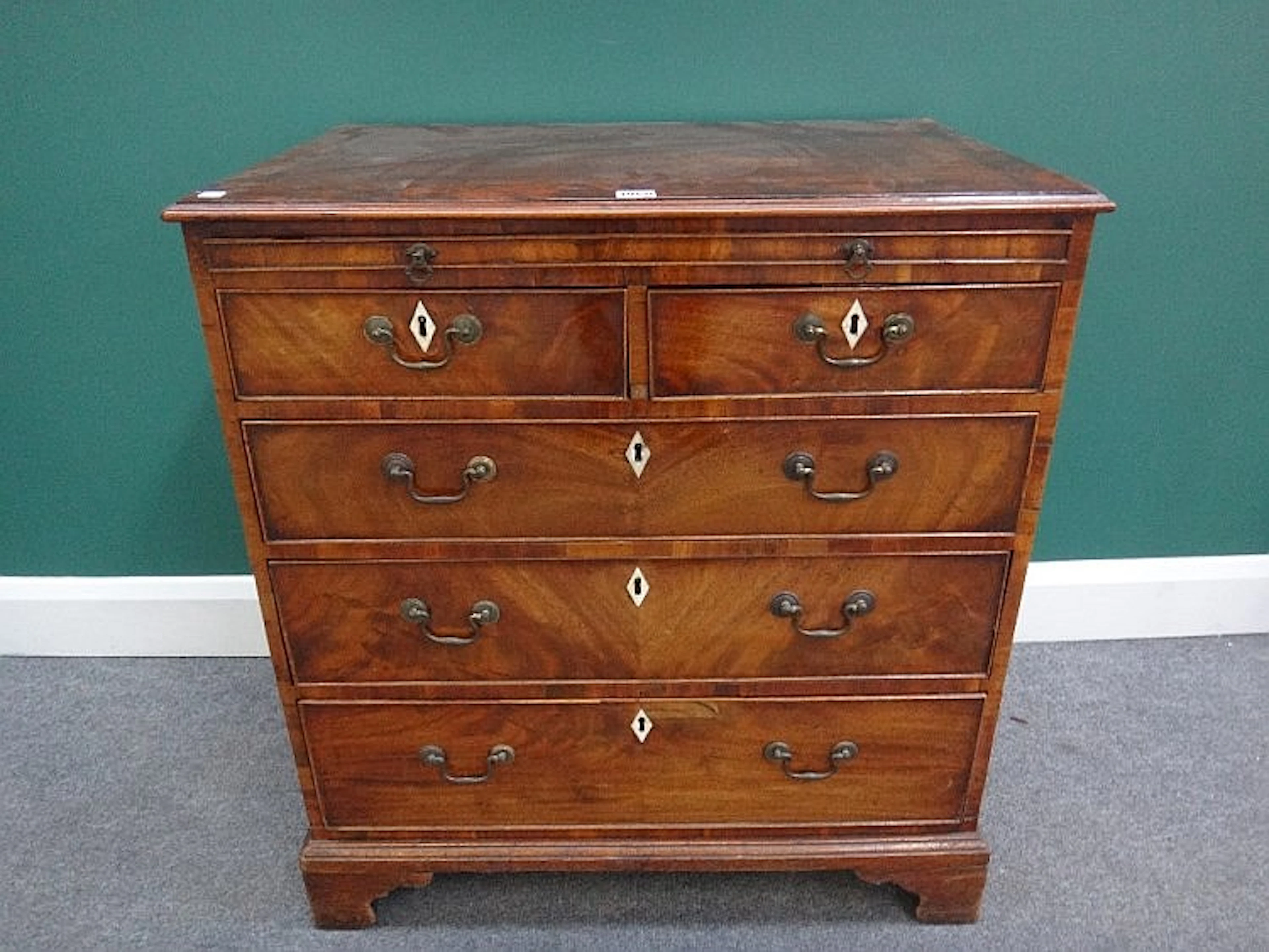 A George III mahogany chest, the brushing slide over two short and three lo