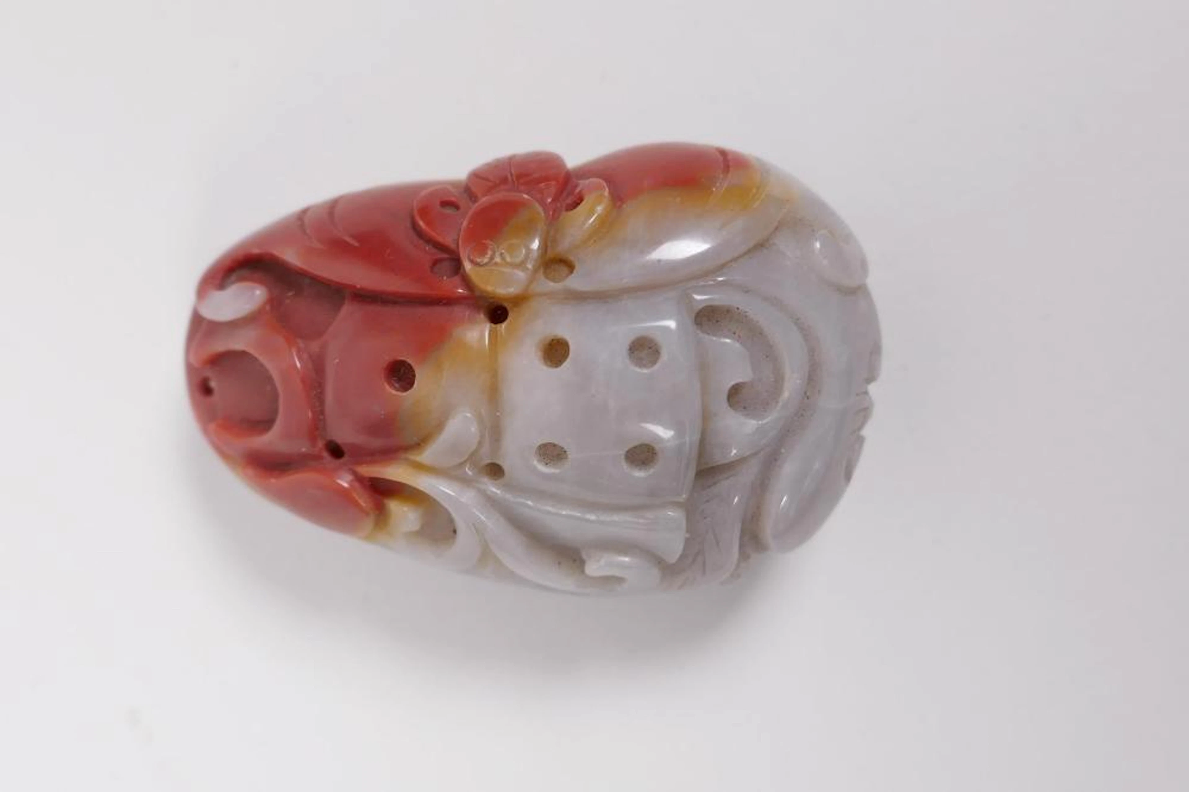 A Chinese russet and grey hardstone pendant with carved bat decoration, 2½"