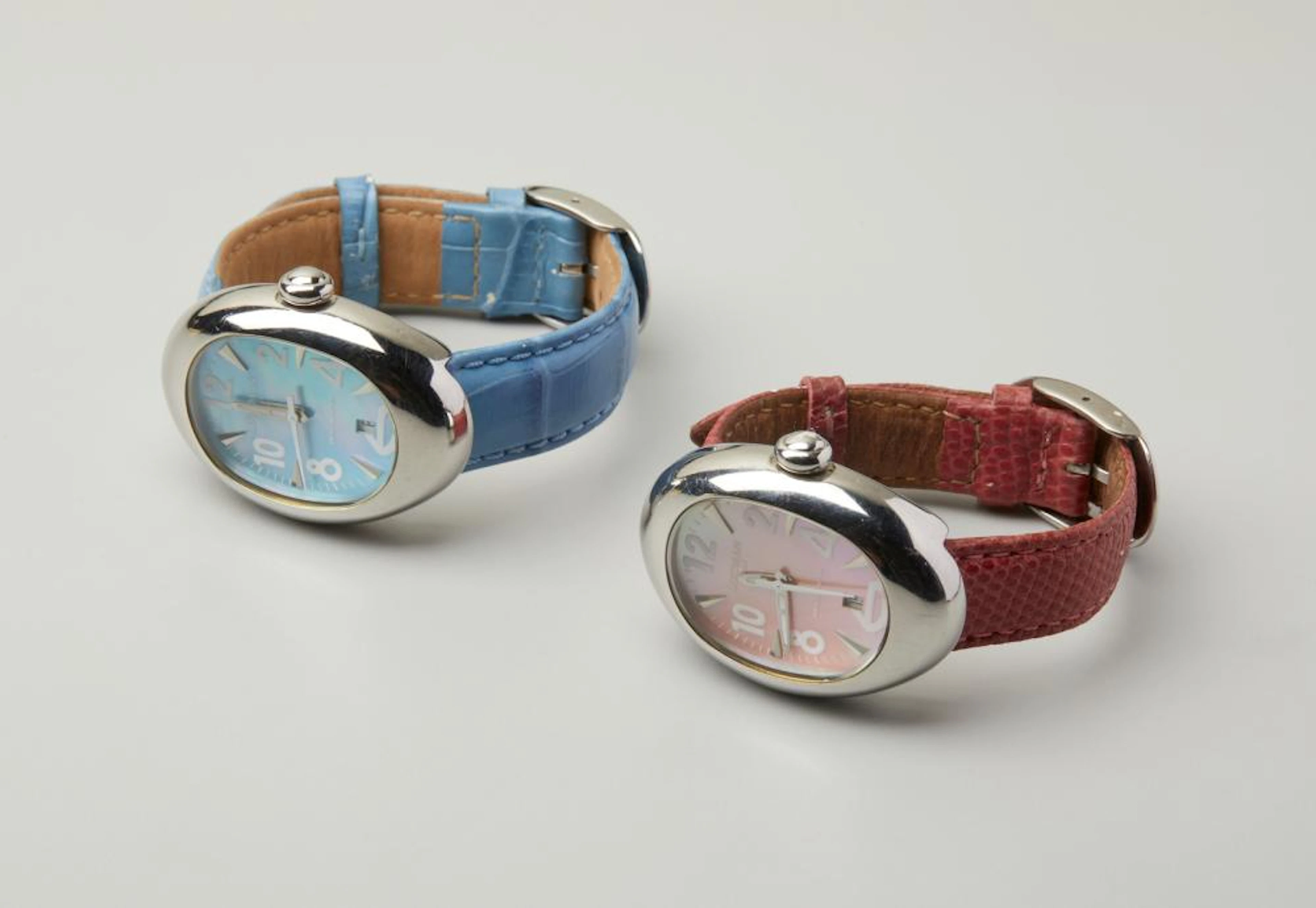 LOCMAN Two steel watches with oval cases with red and light blue bands.