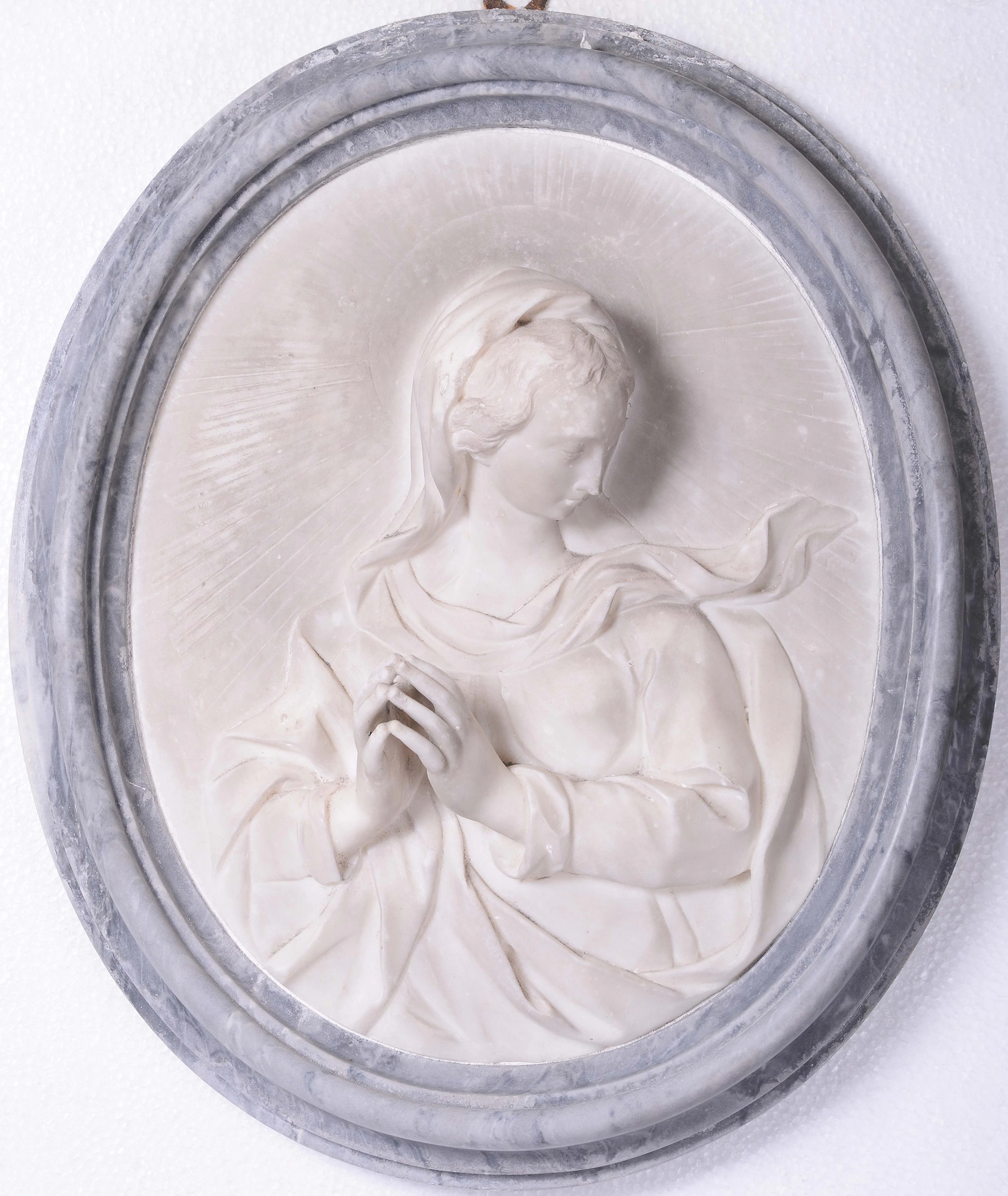 A white oval bas-relief with a bardiglio gray frame containing the