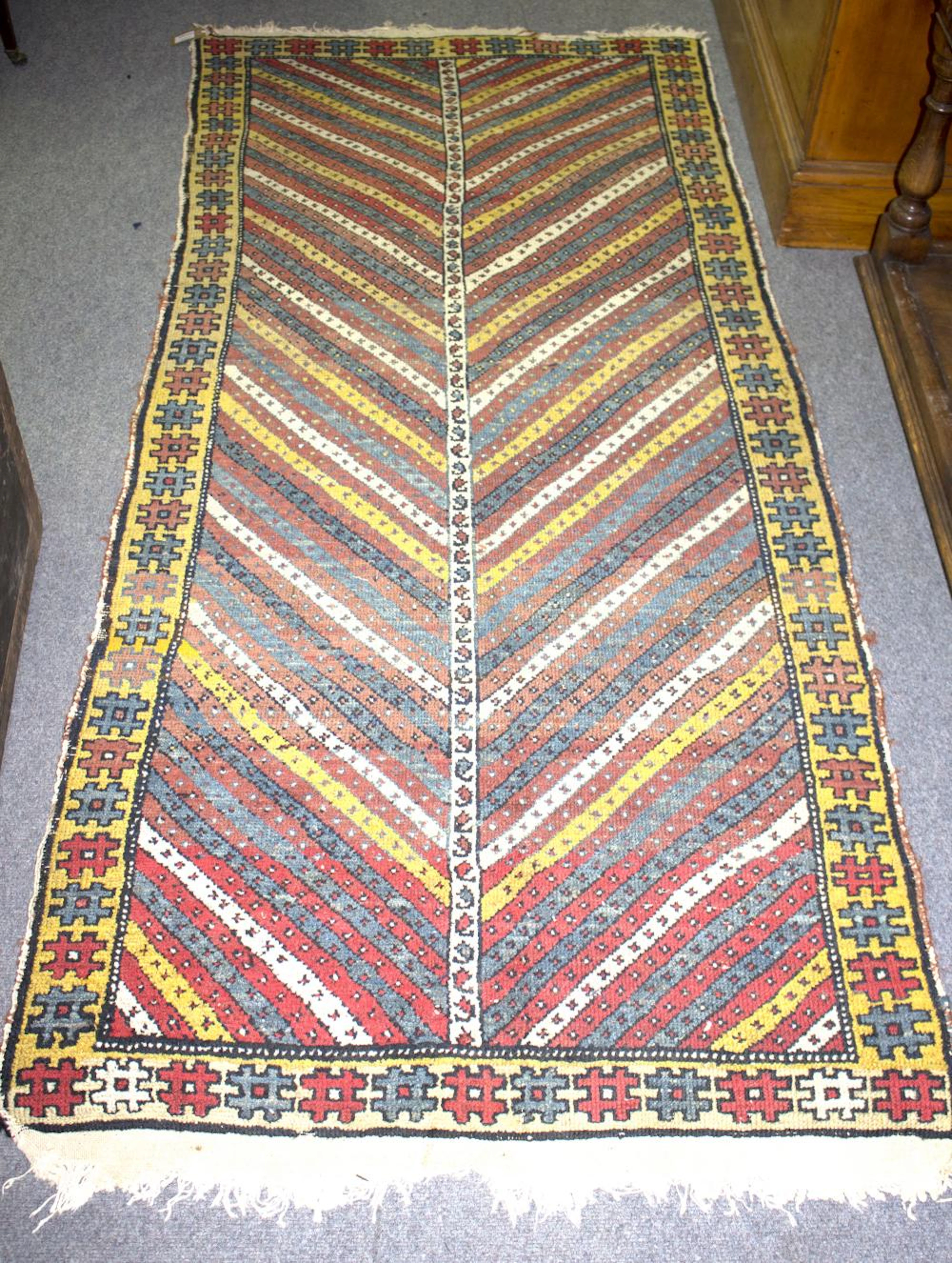 A Gendje rug with central zigzag field within a geometric border, 204cm x 92cm