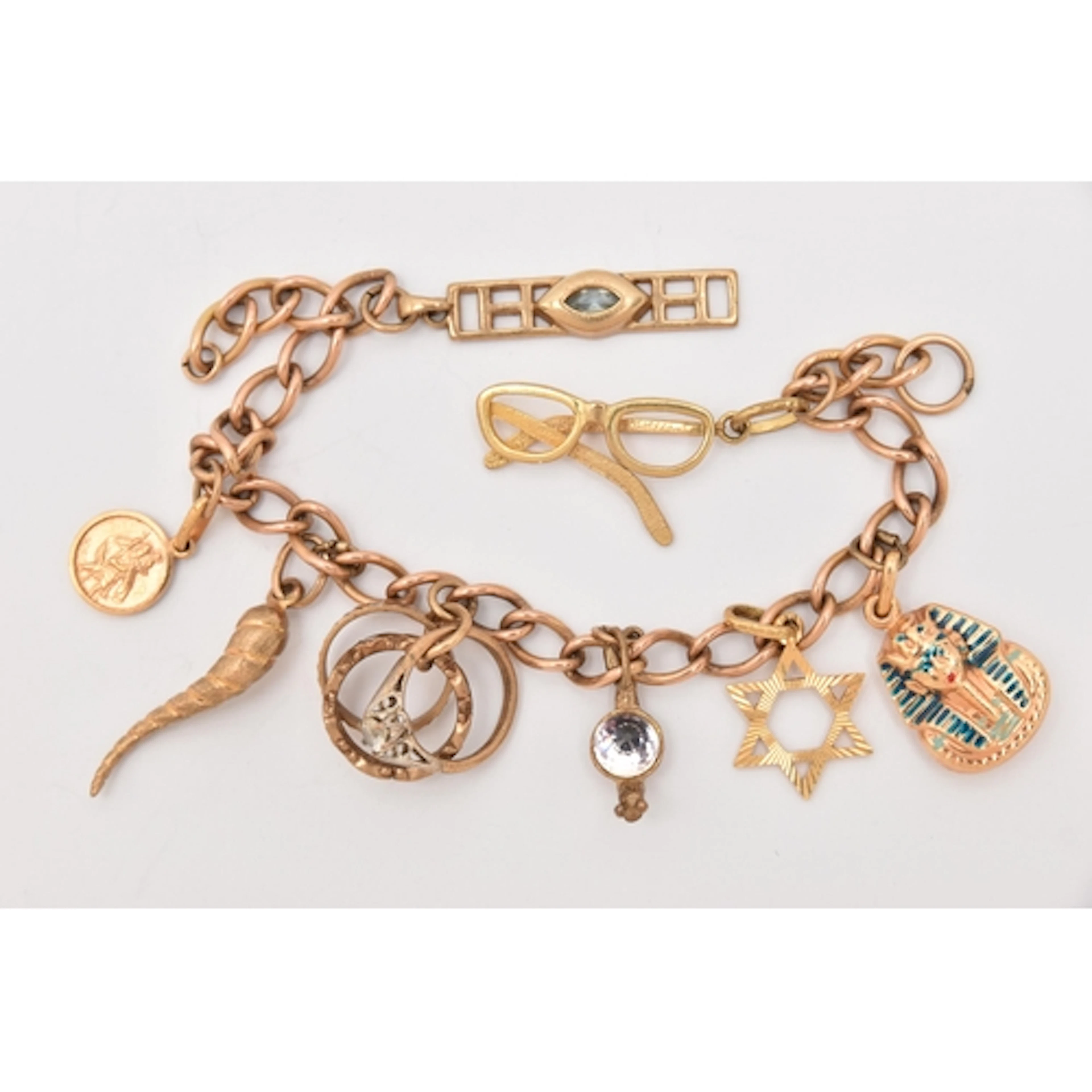 A YELLOW METAL CHARM BRACELET, curb link bracelet links stam...