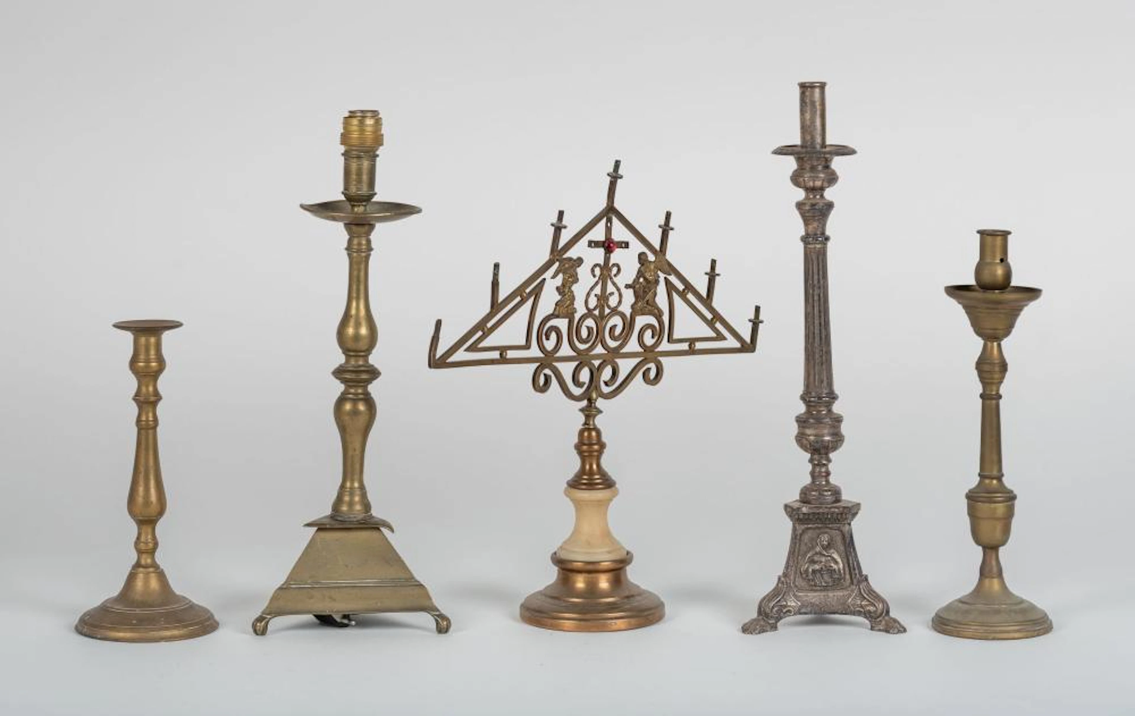 Lote compuesto por cuatro candeleros y un candelabro realizados en bro